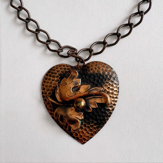 Vintage 1950s hammered copper heart pendant necklace with sculptural leaf motif on chunky copper chain, mid-century modern artisan jewelry.