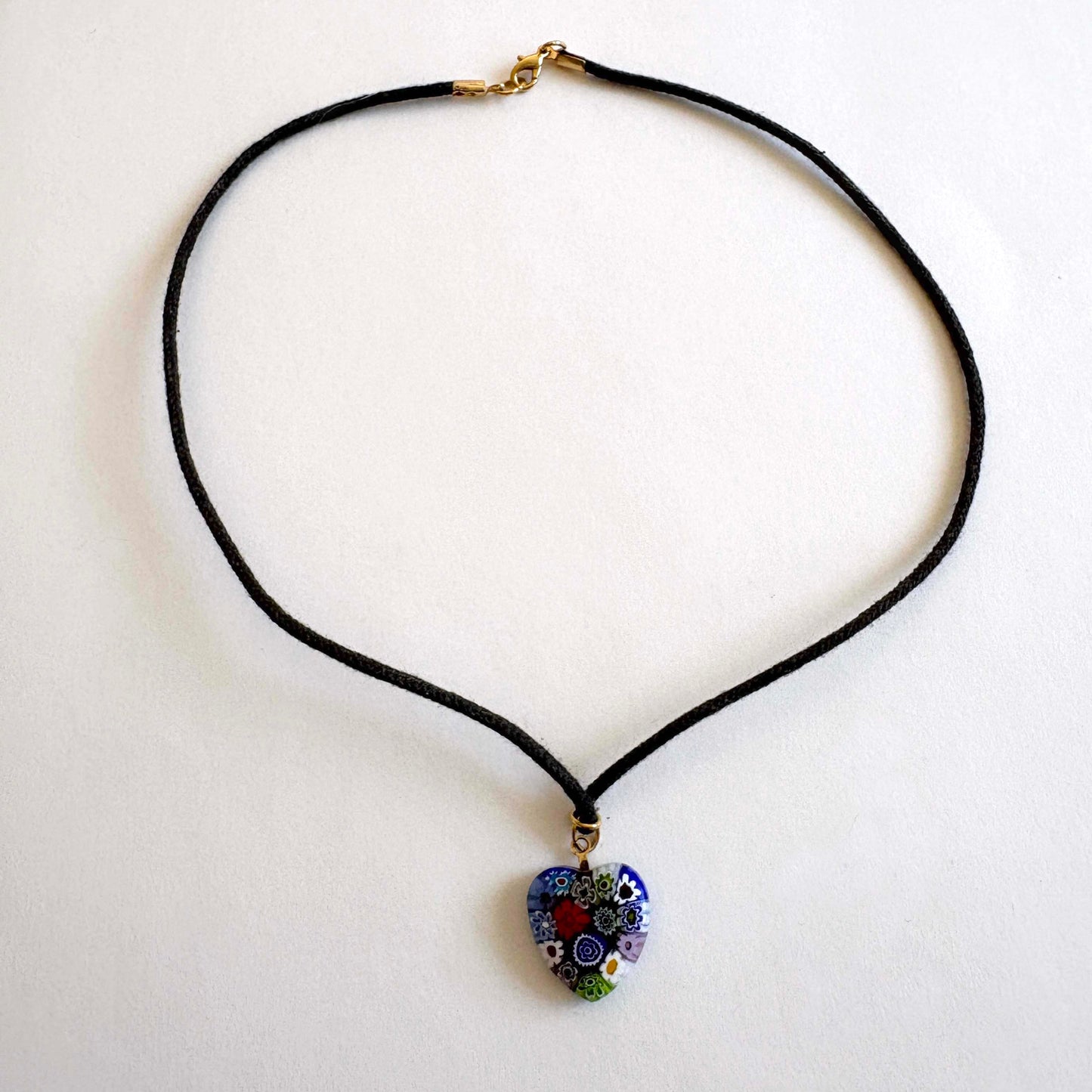Murano millefiori glass heart necklace with multicolor floral pattern on black cord with gold-tone accents on white background