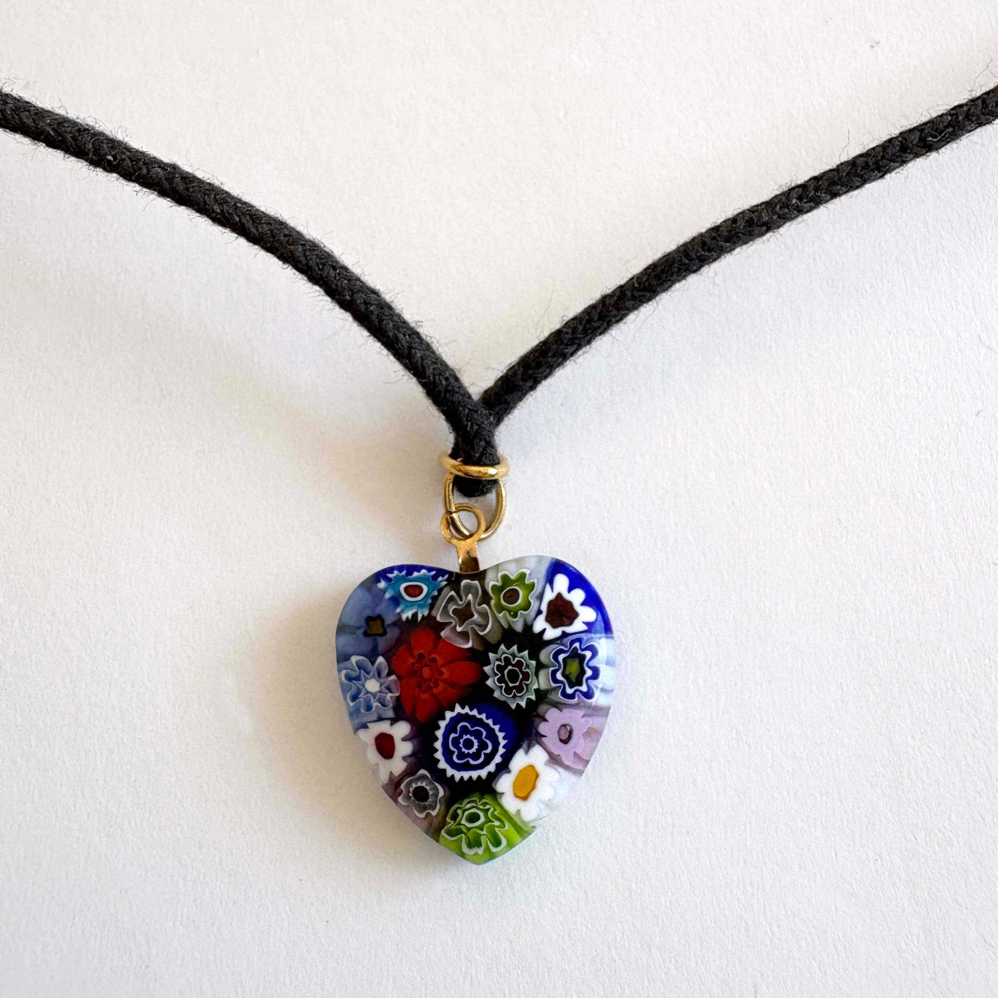 Murano millefiori glass heart necklace with multicolor floral pattern on black cord with gold-tone accents on white background