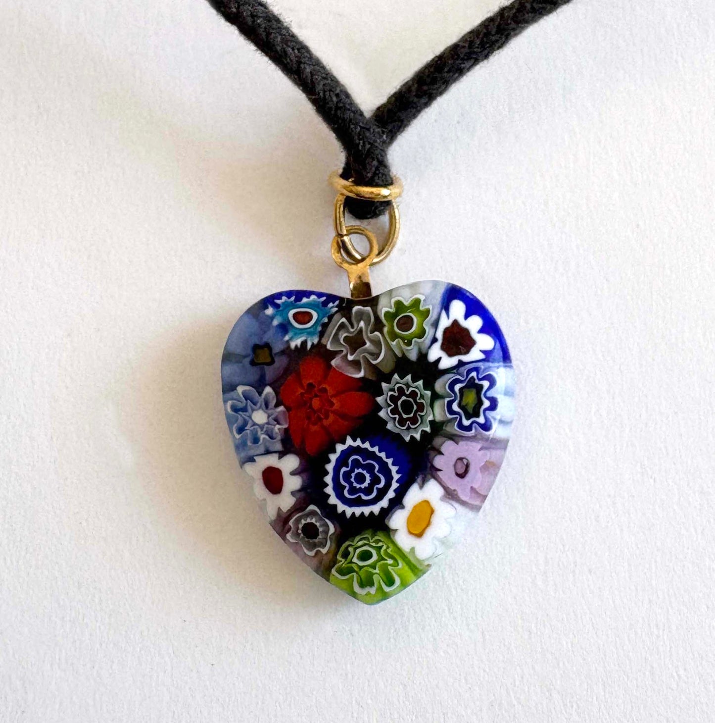 Murano millefiori glass heart necklace with multicolor floral pattern on black cord with gold-tone accents on white background