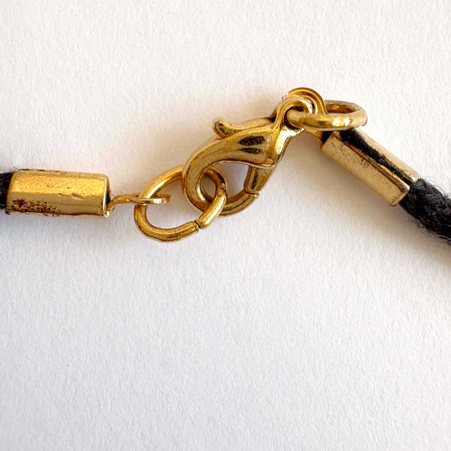 black cord clasp with gold-tone accents on white background