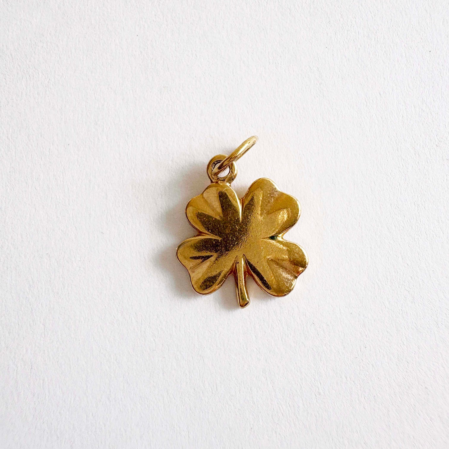 Gold four-leaf clover pendant on a white background