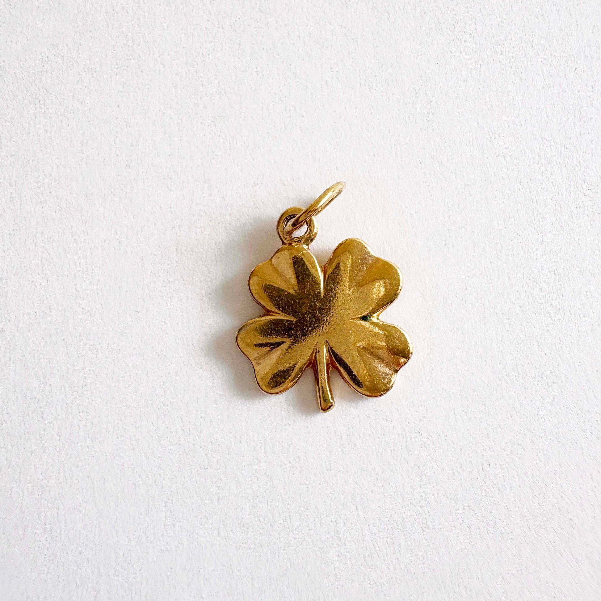 Gold four-leaf clover pendant on a white background