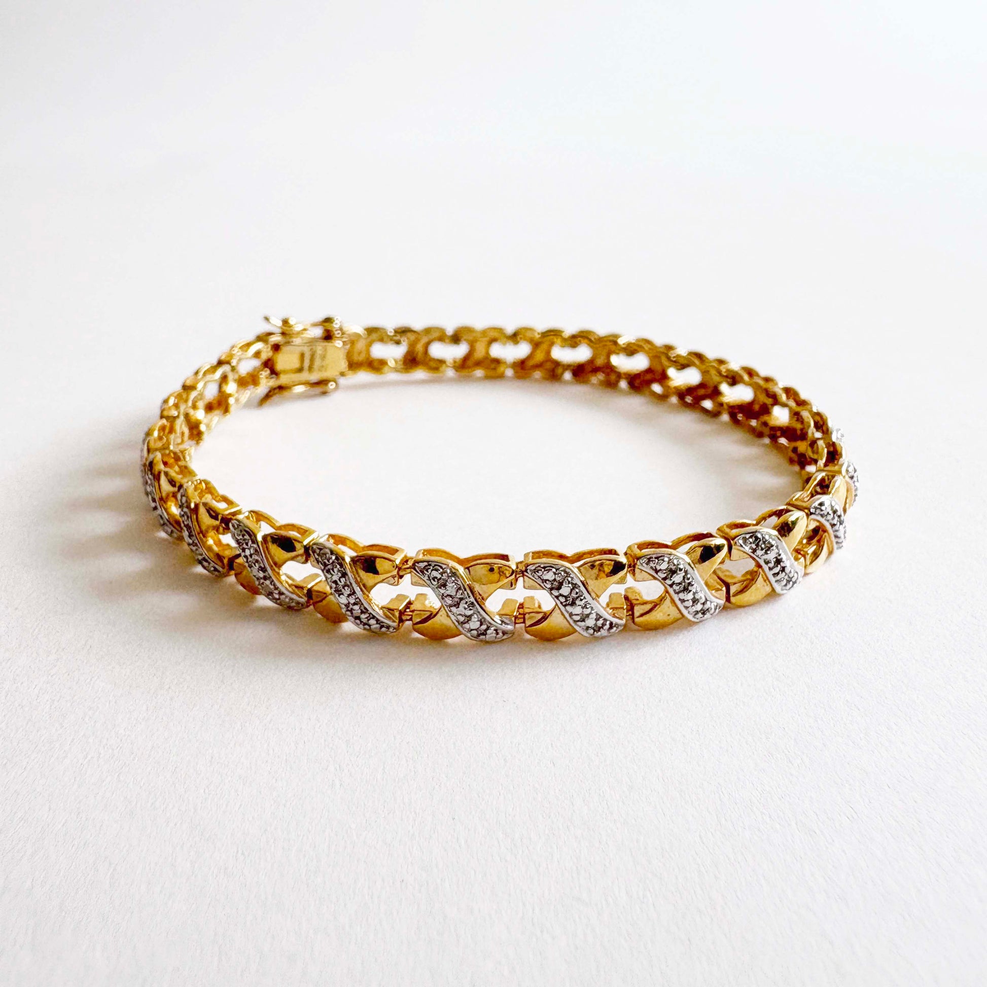 Gold bracelet with interwoven X-link design on a white background