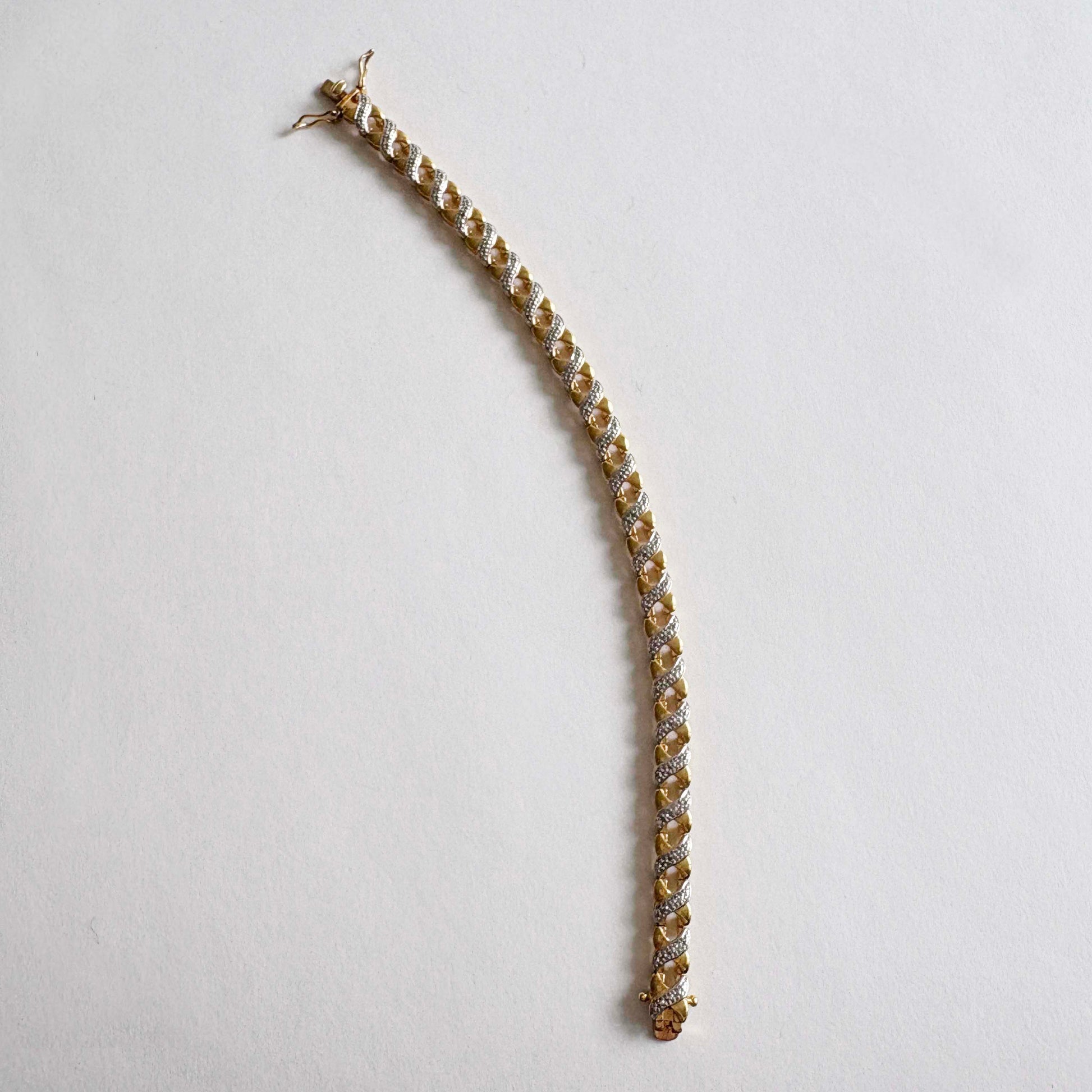 Gold bracelet with clear stones on a light gray background