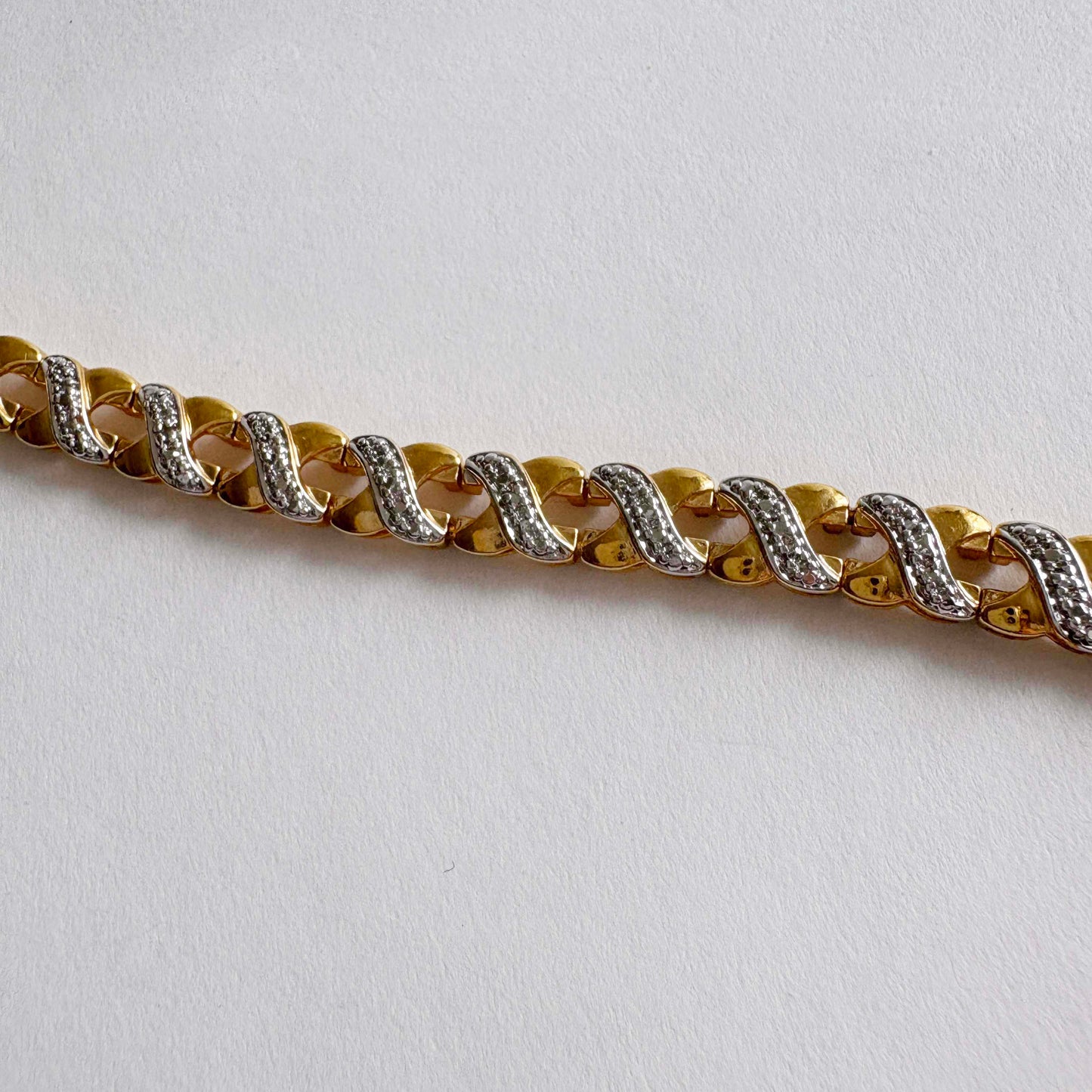 Gold and silver chain bracelet on a light gray background