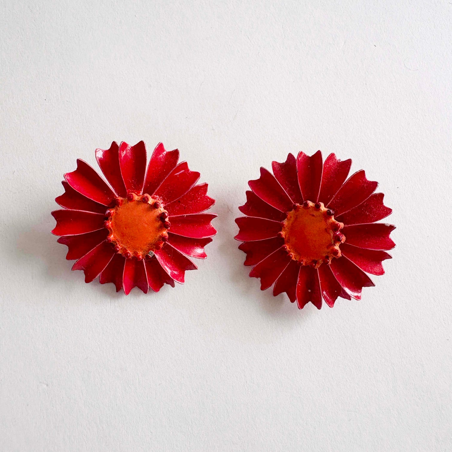 Pair of Vintage red enamel daisy clip-on earrings with orange center from the 1960s.