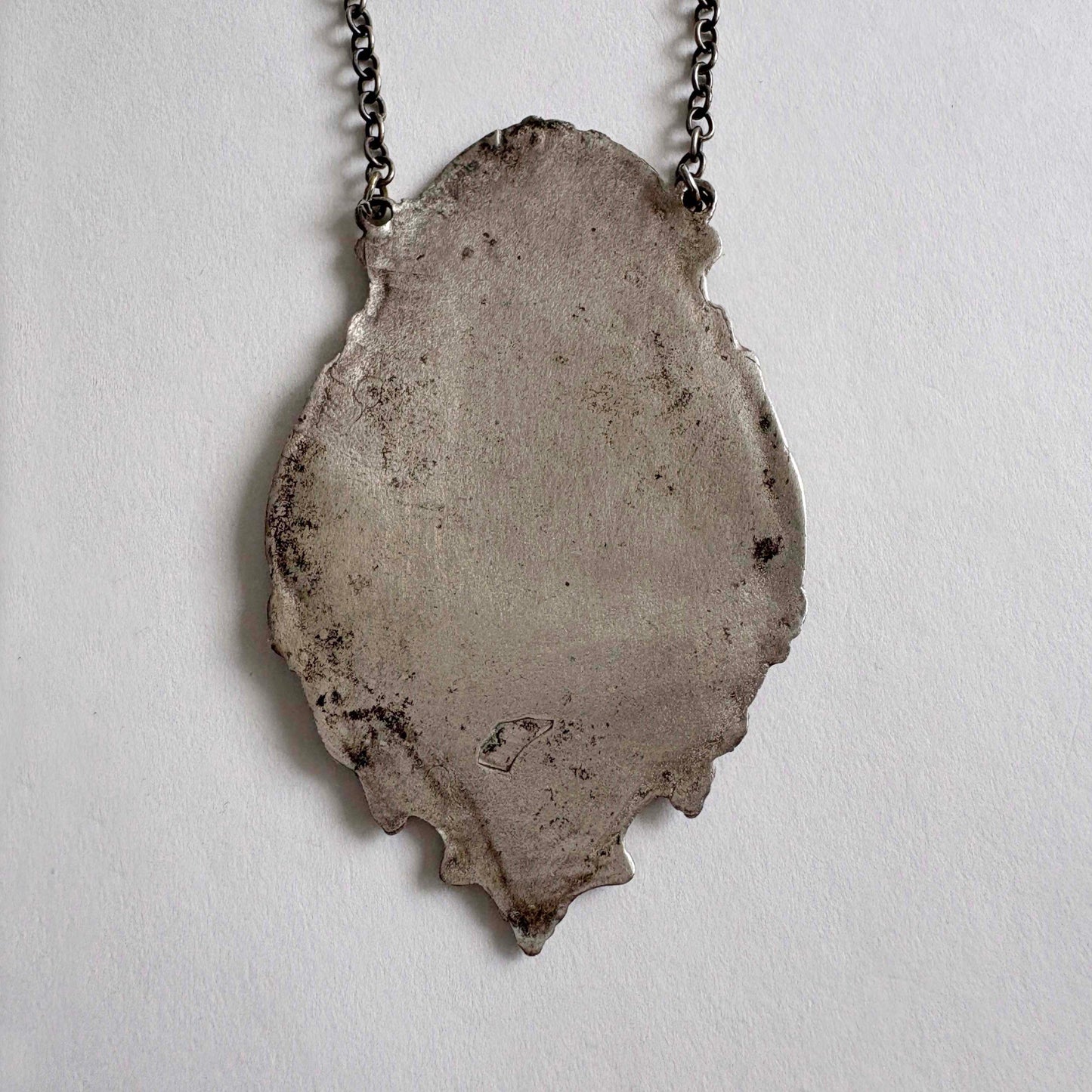sterling wine bottle tag back on a chain against a light gray background