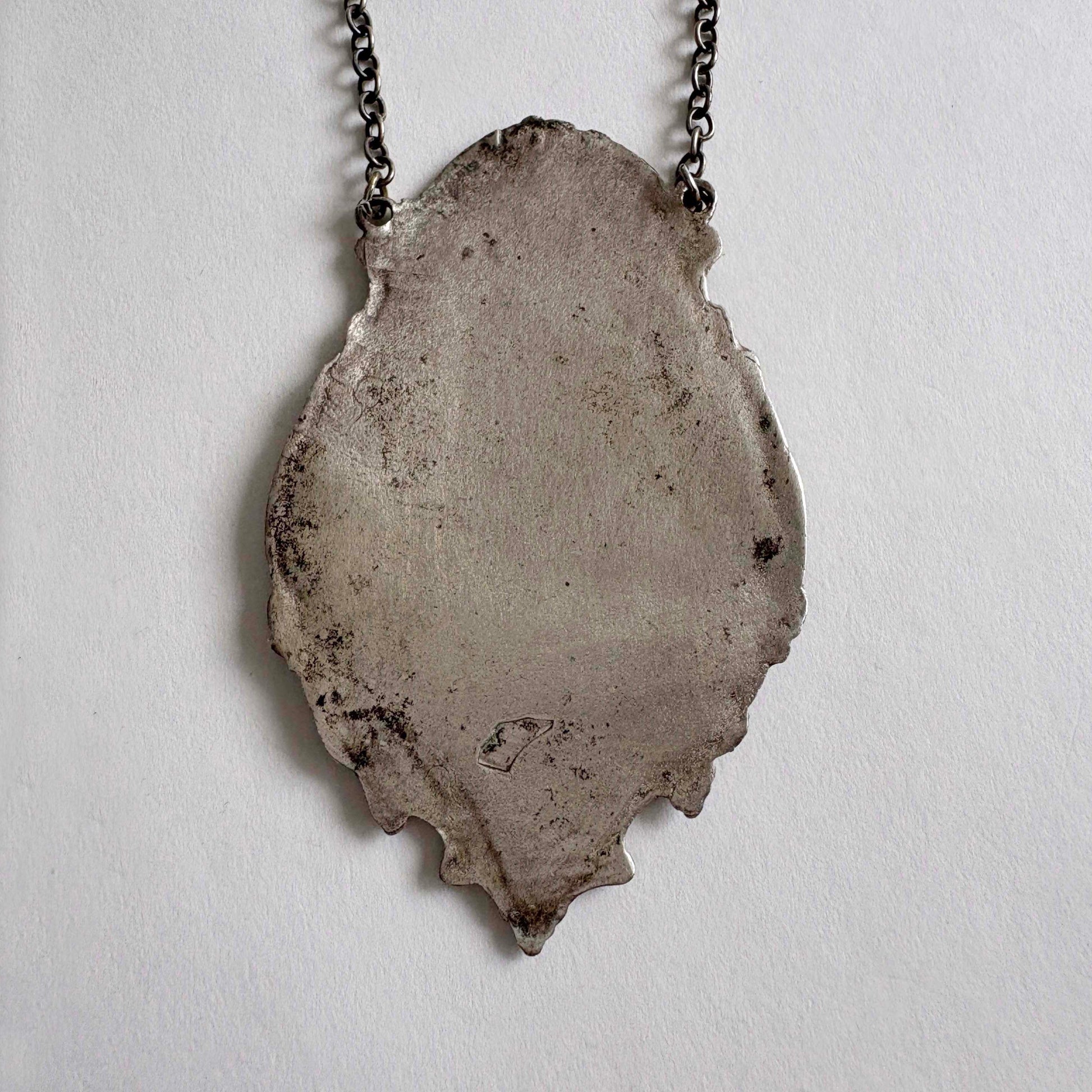 sterling wine bottle tag back on a chain against a light gray background