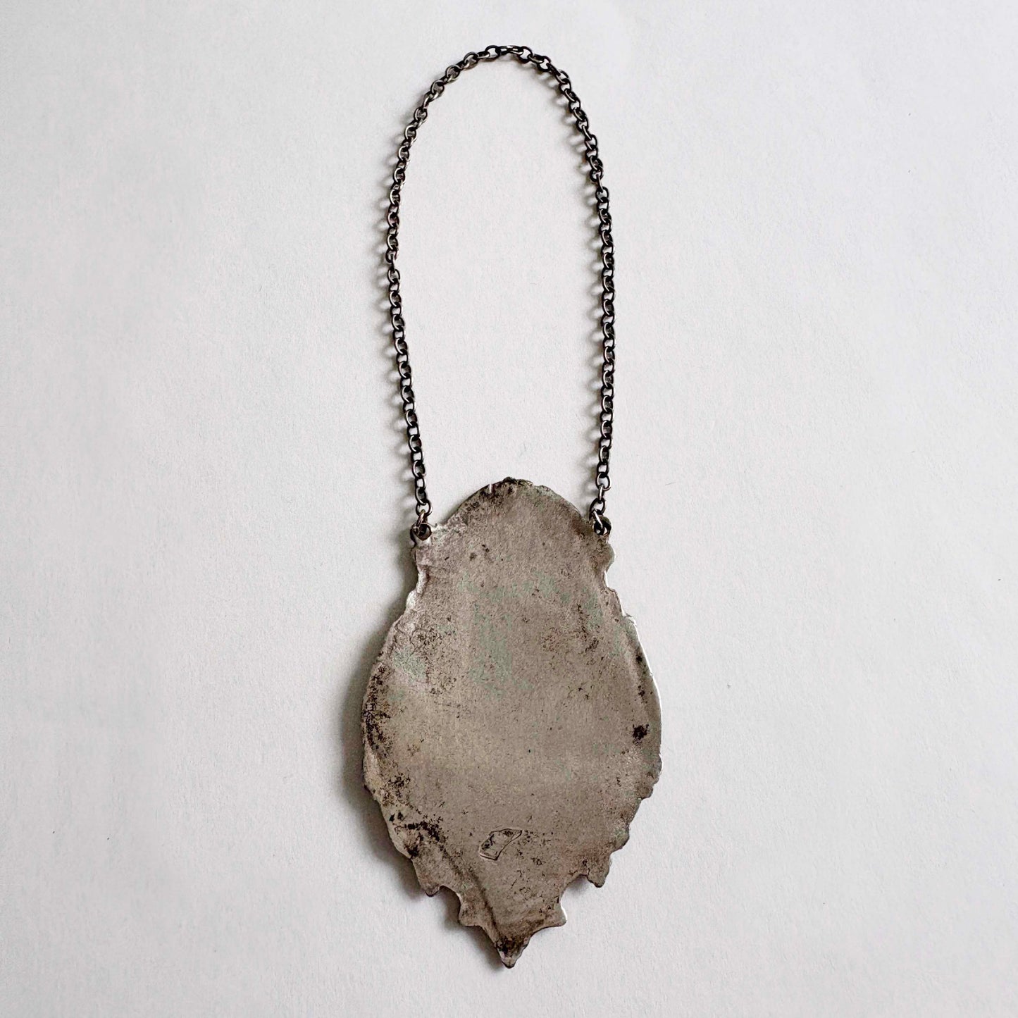sterling wine bottle tag on a chain against a light gray background