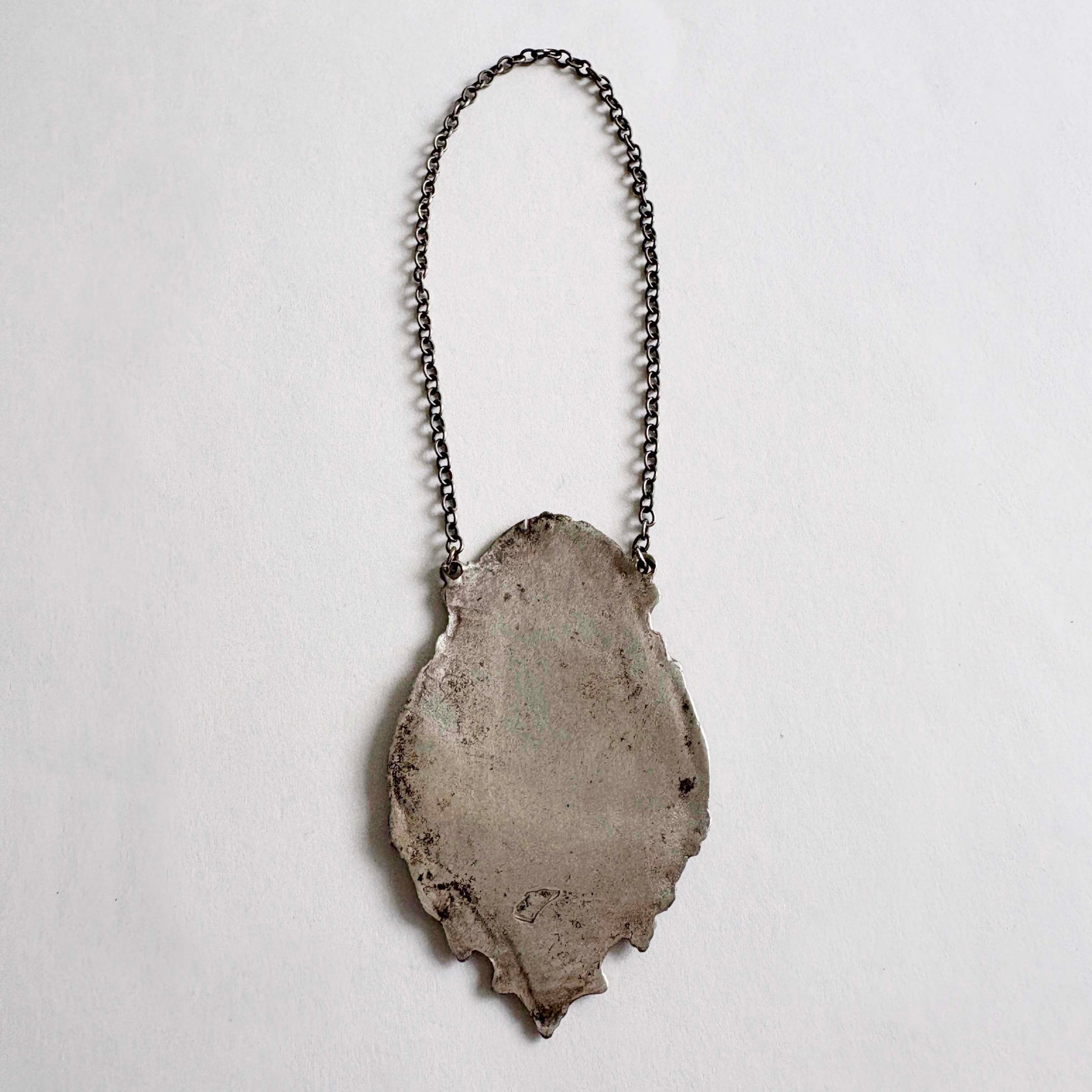 sterling wine bottle tag on a chain against a light gray background