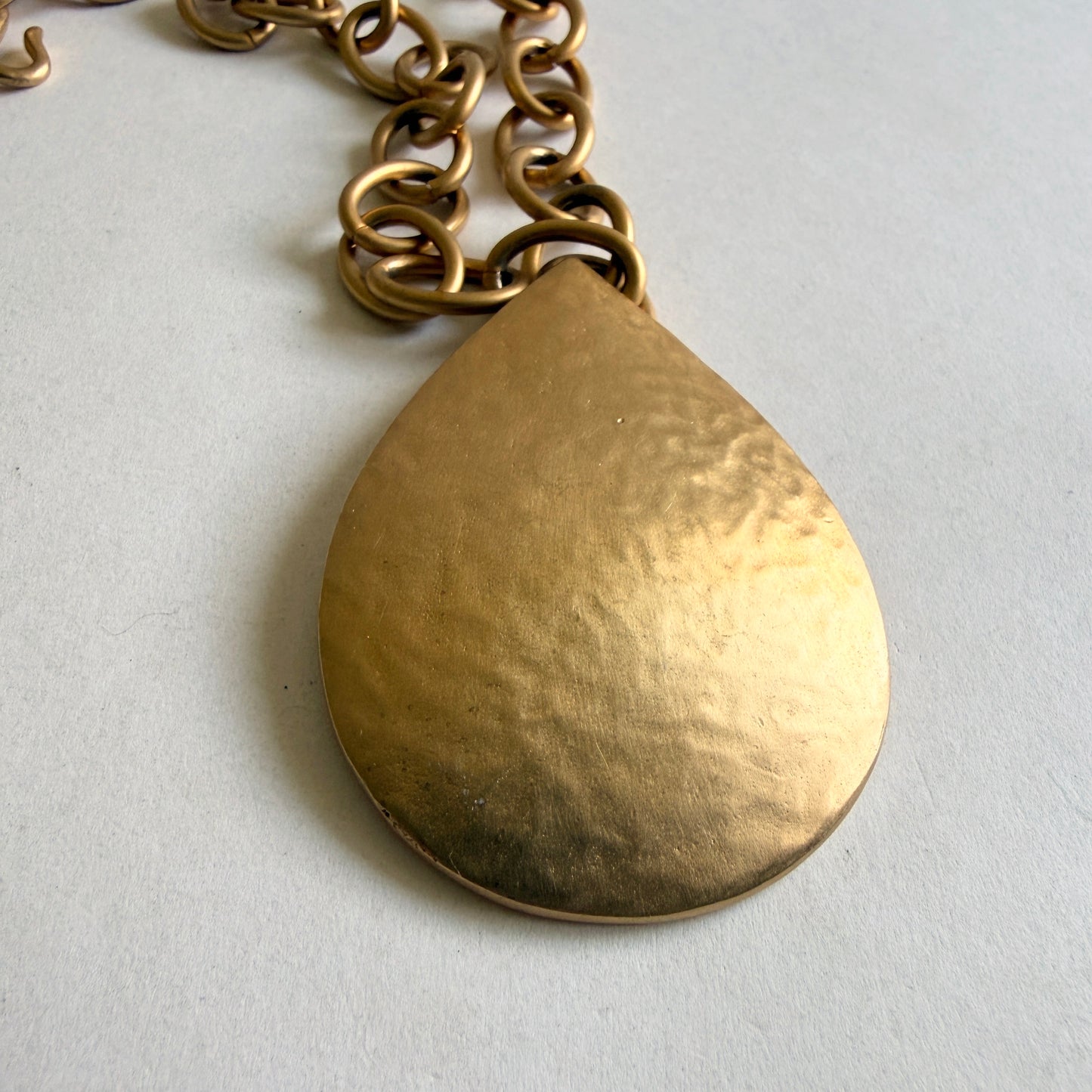Close up of Kenneth Jay Lane oval plaque and Made in USA hallmark tag on vintage necklace