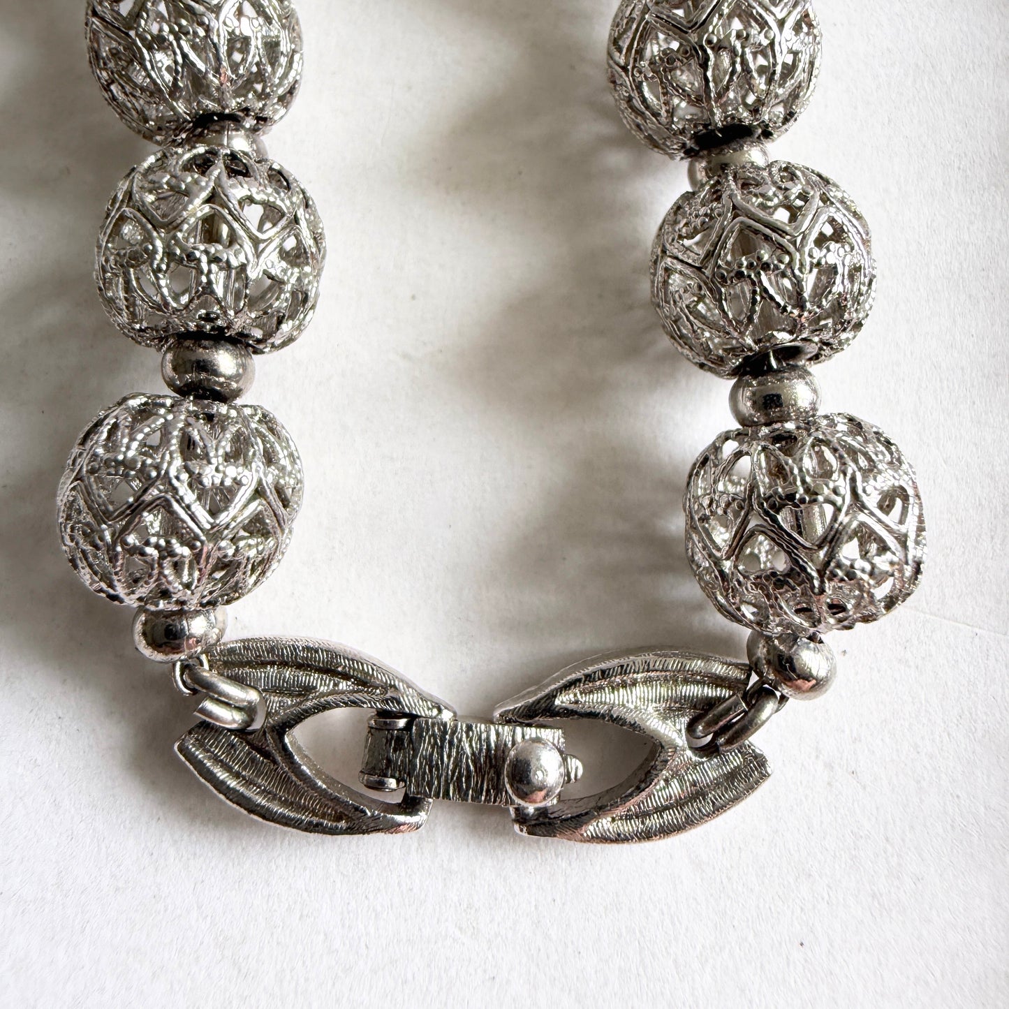 A detailed view of the textured silver-tone fold-over clasp, highlighting the mechanical quality and craftsmanship.