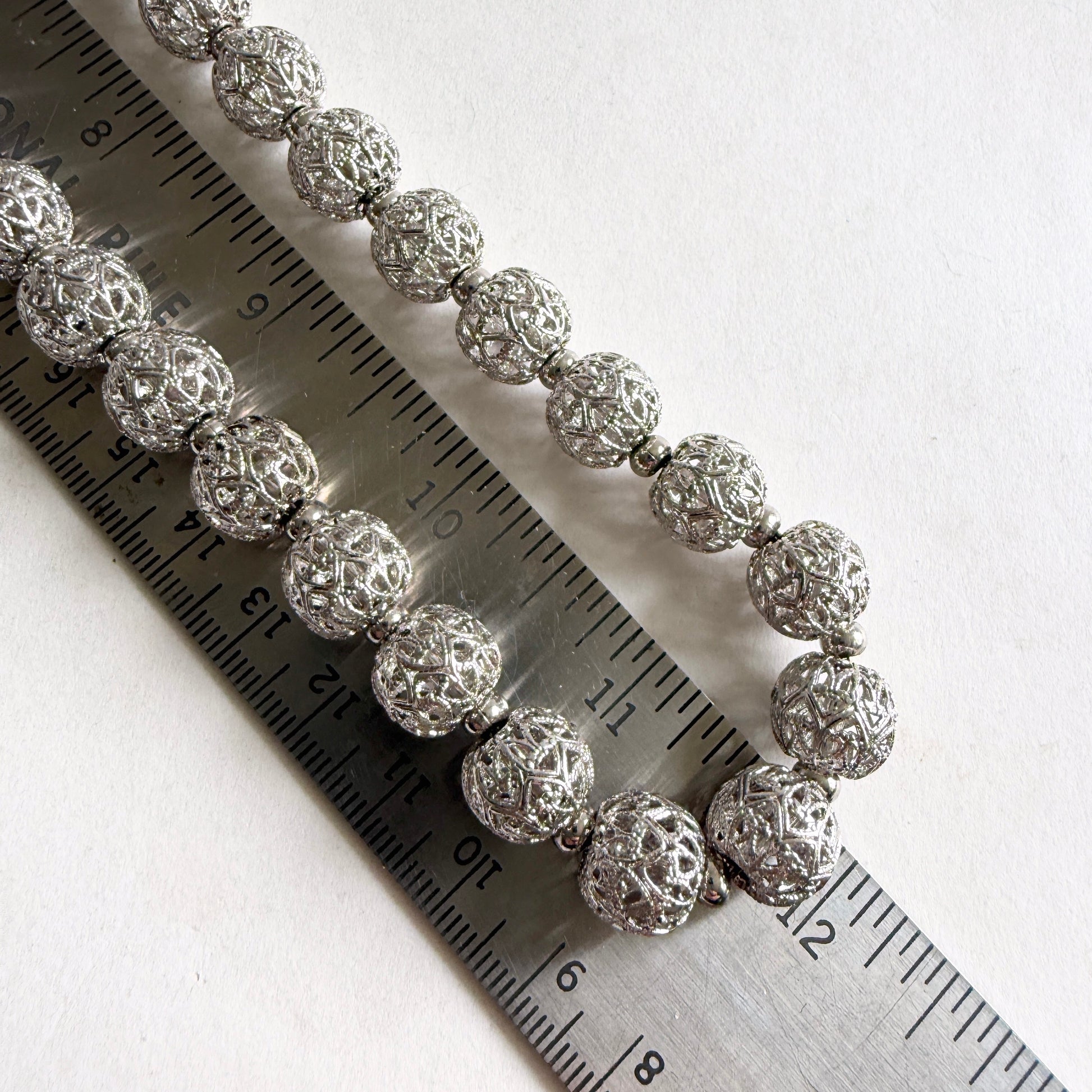 Silver beaded bracelet on a ruler for size reference
