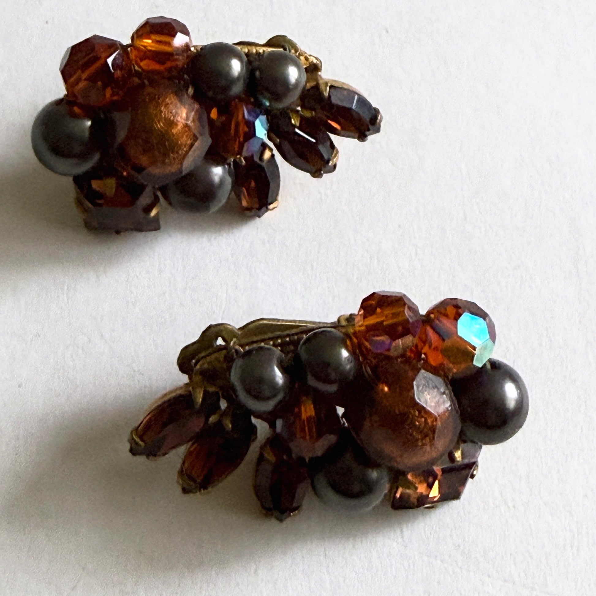 Pair of vintage-style earrings with brown and black beads on a white background