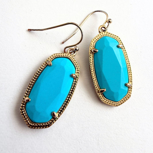 Turquoise earrings with gold frames on a white background