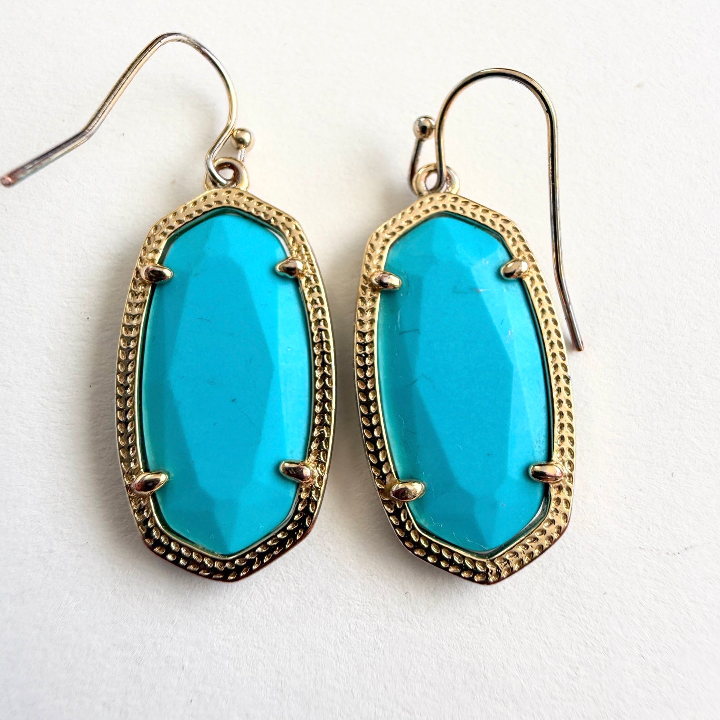 Turquoise earrings with gold frames on a white background