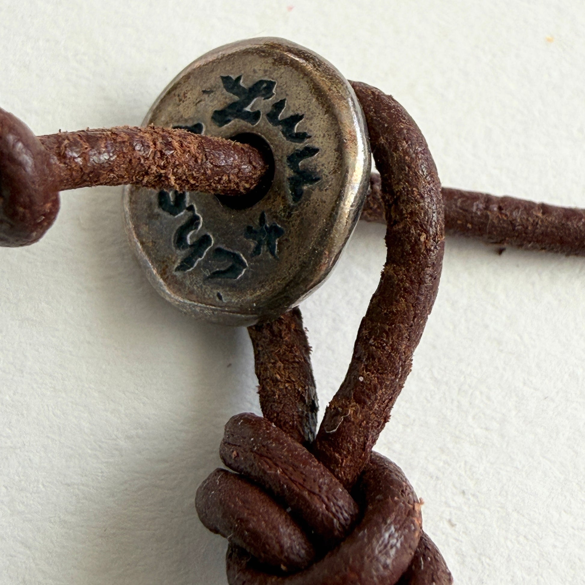 Close-up of a brown leather bracelet with a metal clasp on a white background