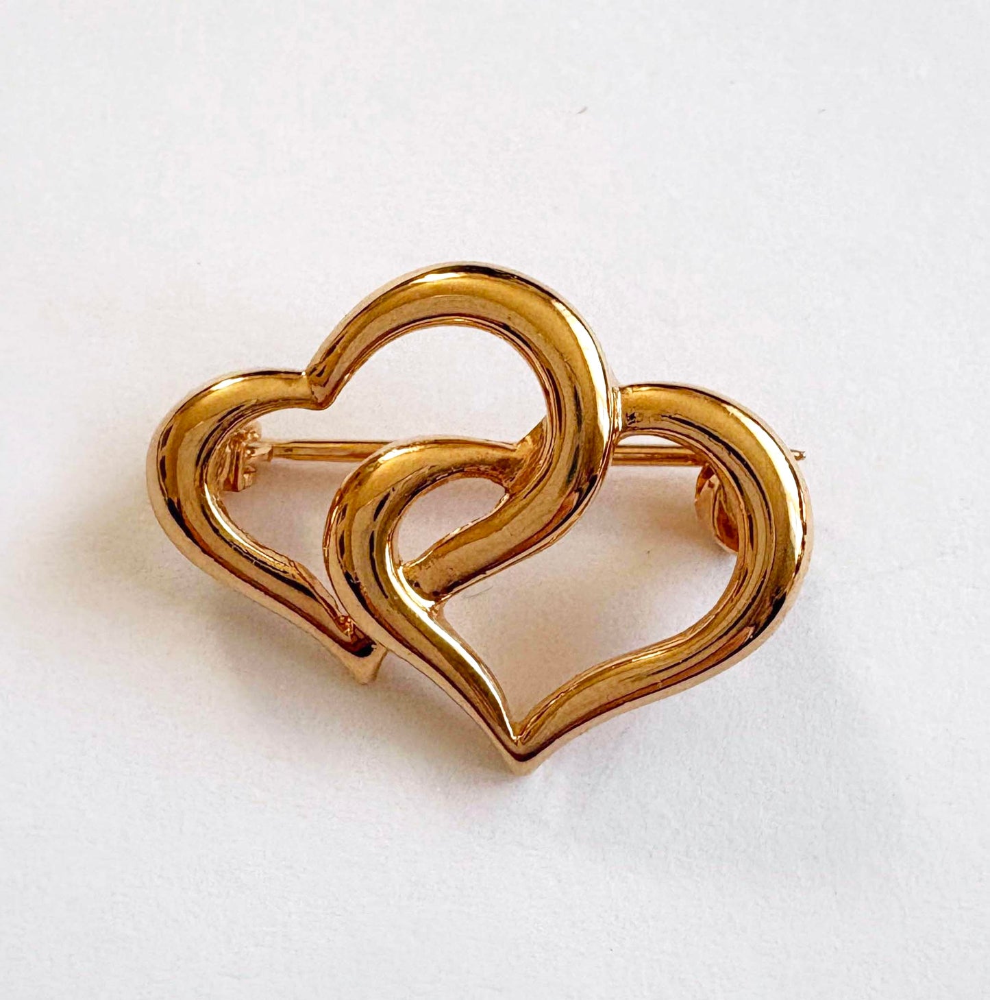 Gold heart-shaped brooch on a white background