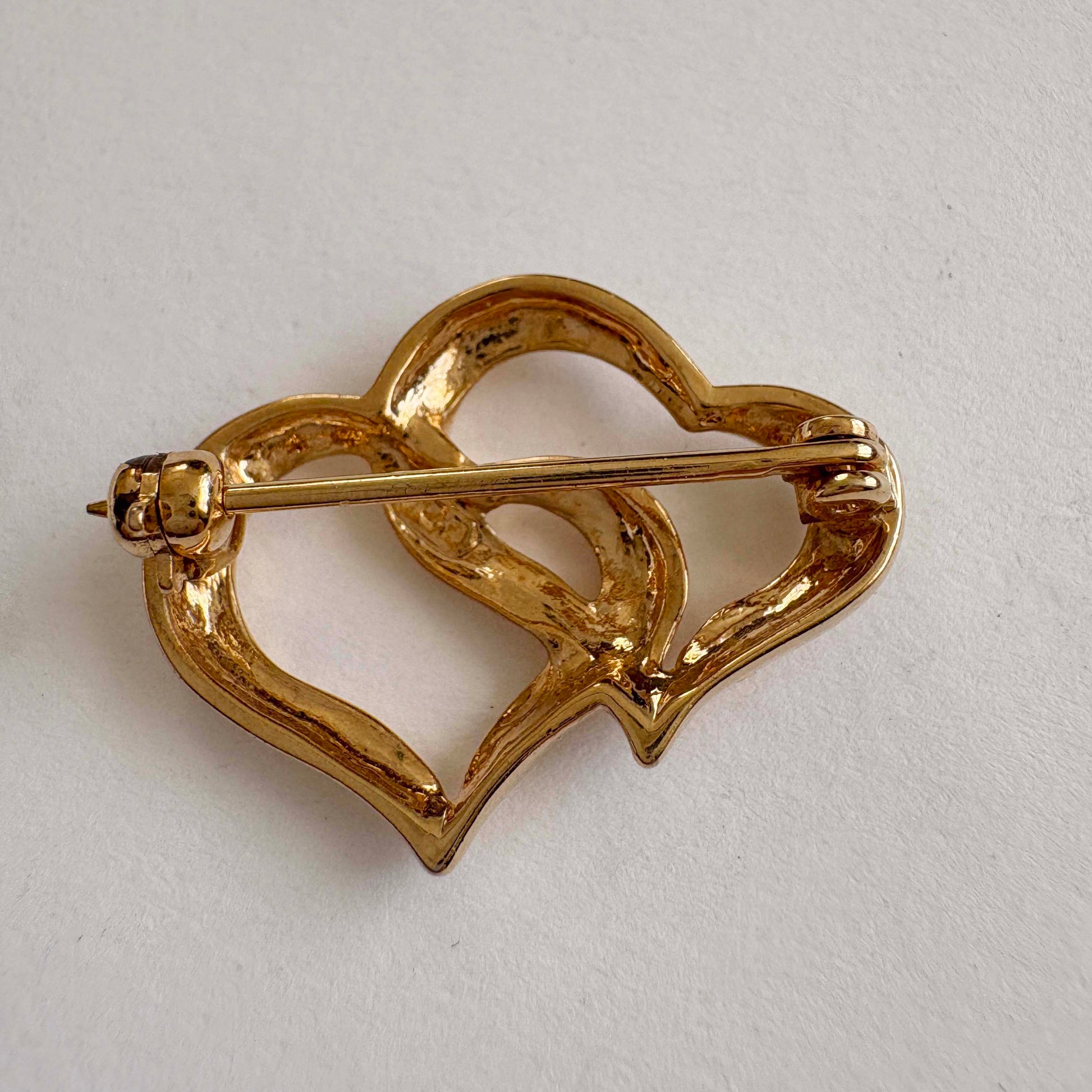 Gold heart-shaped brooch on a light gray background