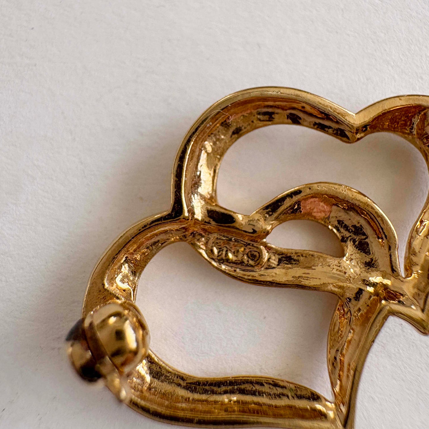 Gold heart-shaped brooch on a white background