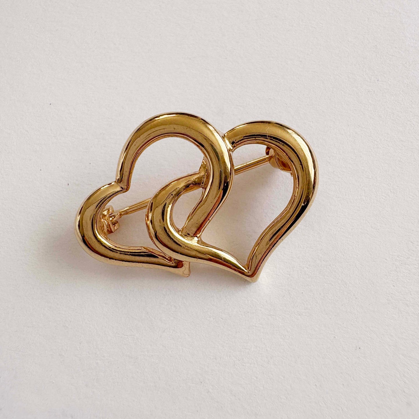 Gold heart-shaped brooch on a light gray background