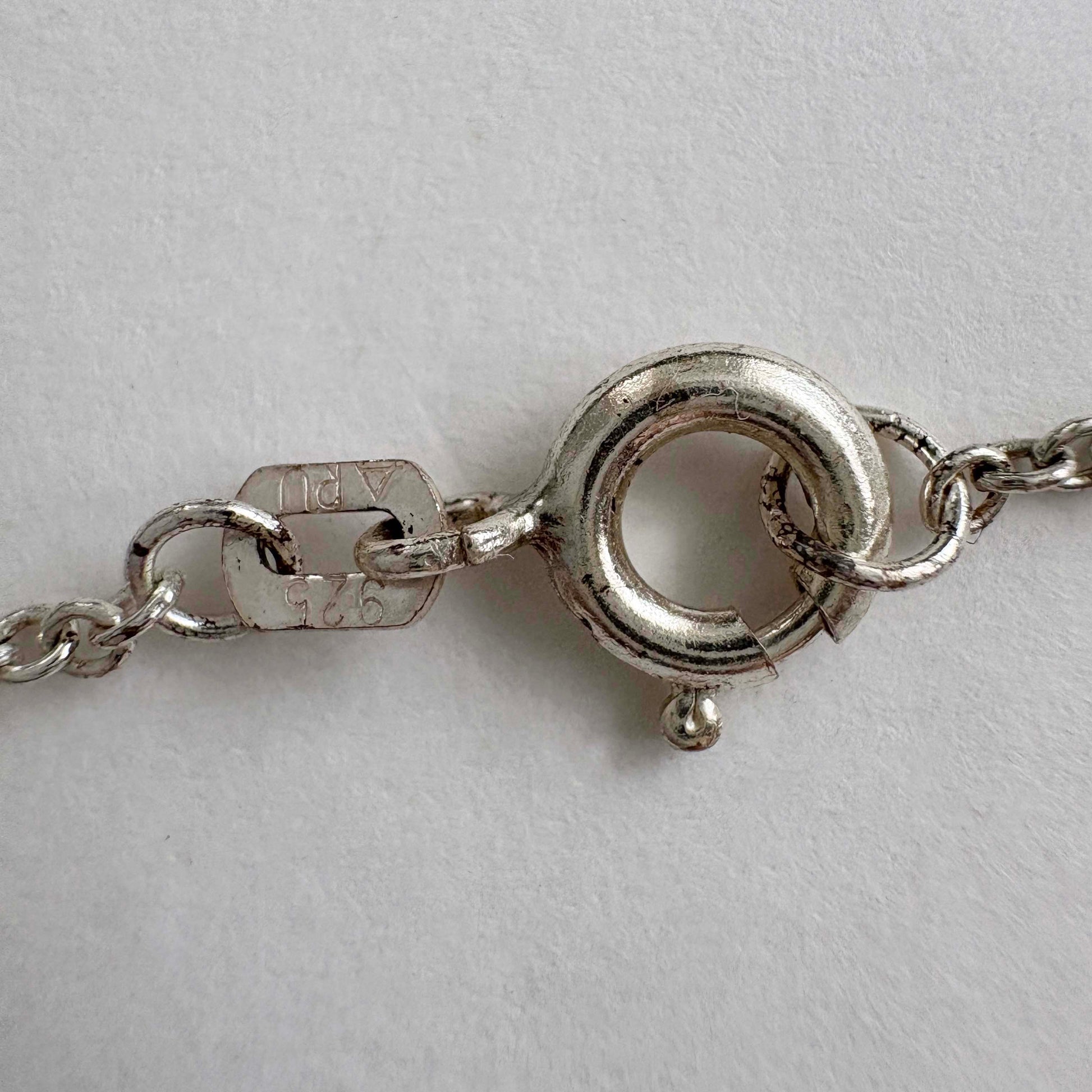 close-up of a silver necklace clasp on a light gray background