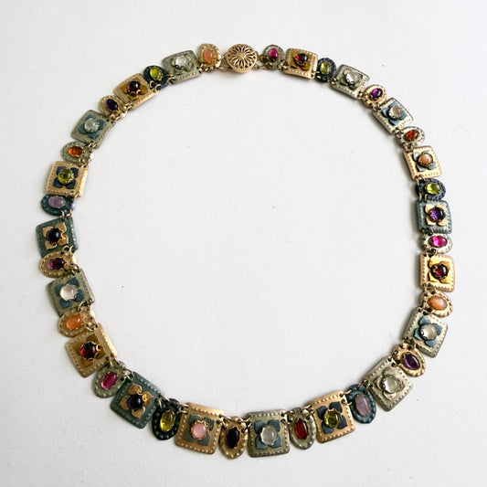 gold multicolored gemstone necklace on a white background