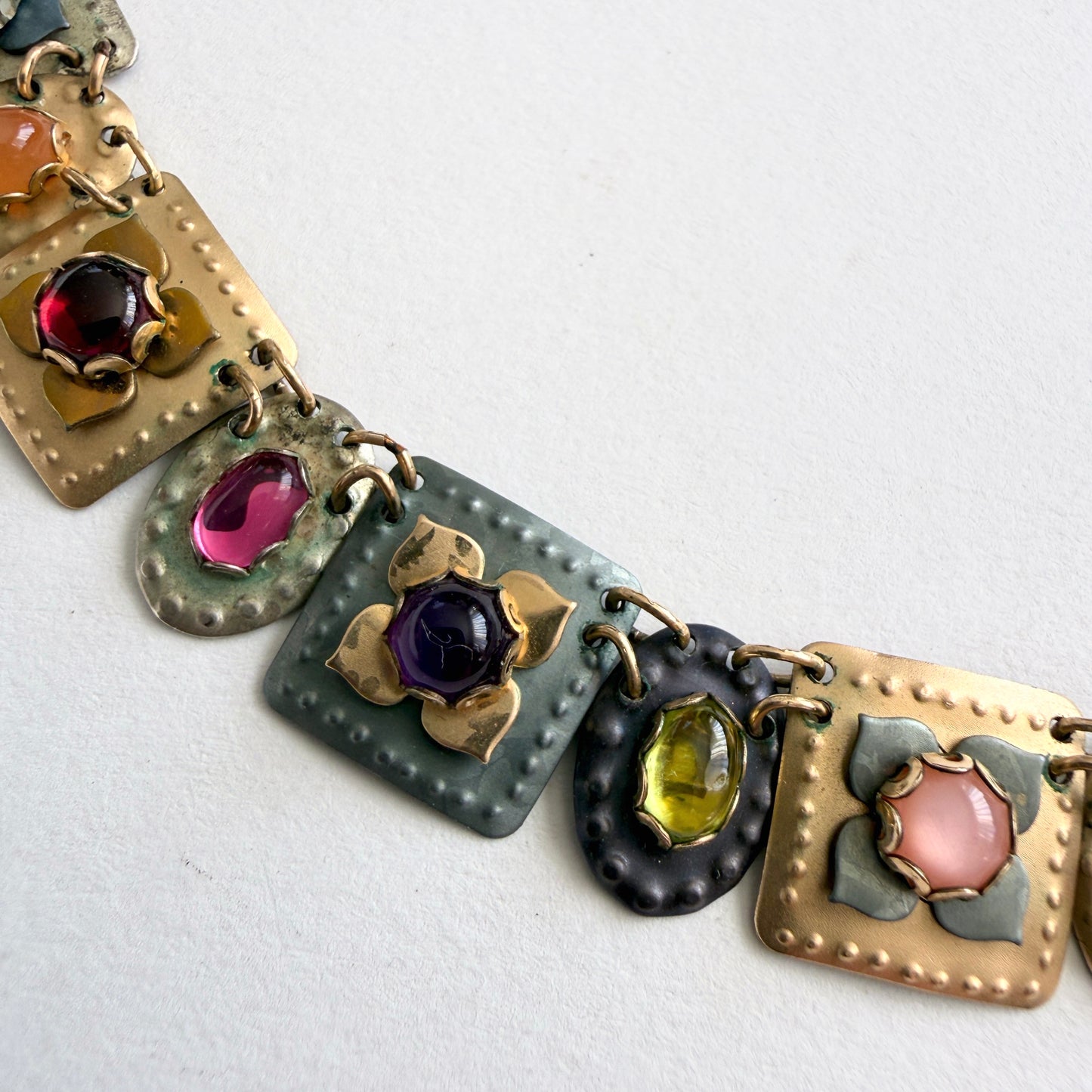 Colorful gemstone gold necklace on a light gray background
