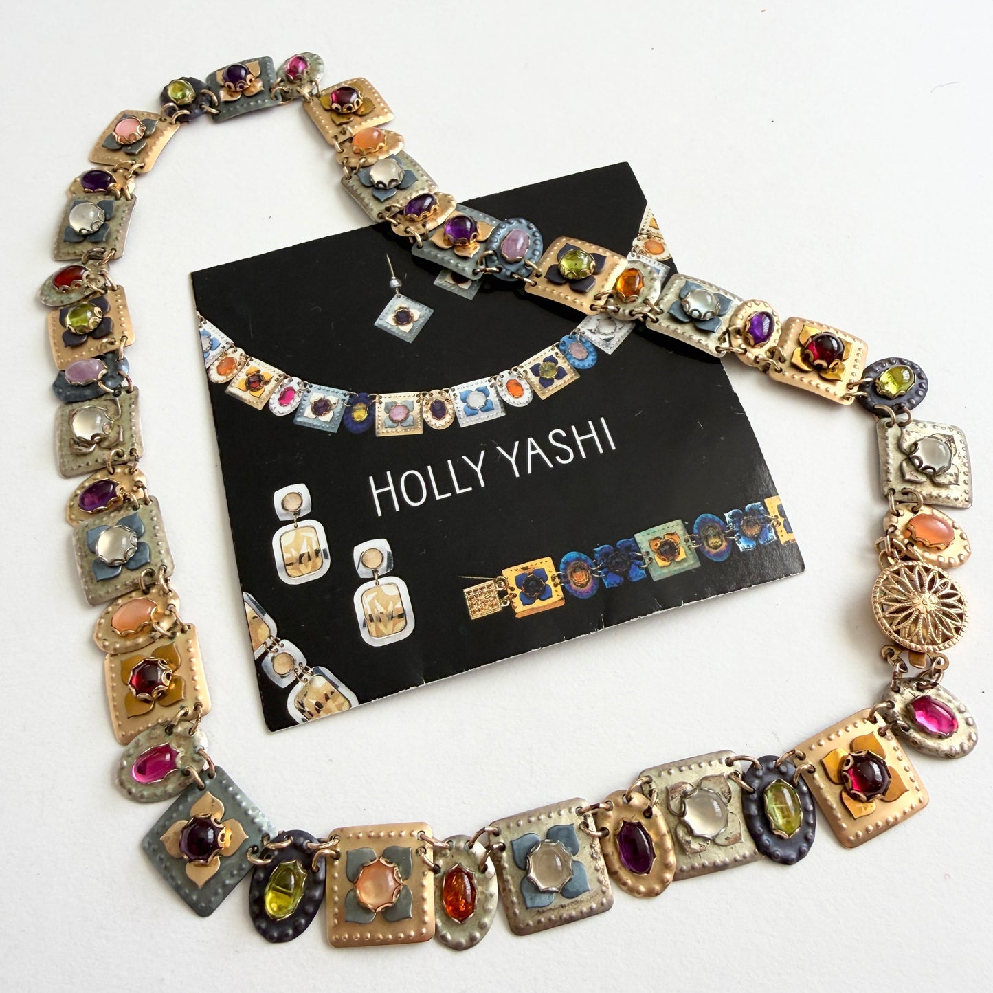 Colorful gemstone gold necklace on a light gray background