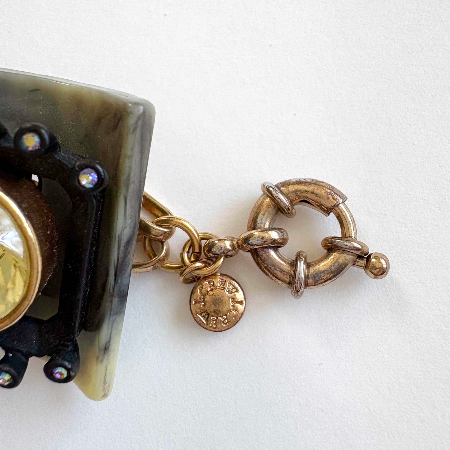 Close-up of a gold bracelet with a clasp on a white background