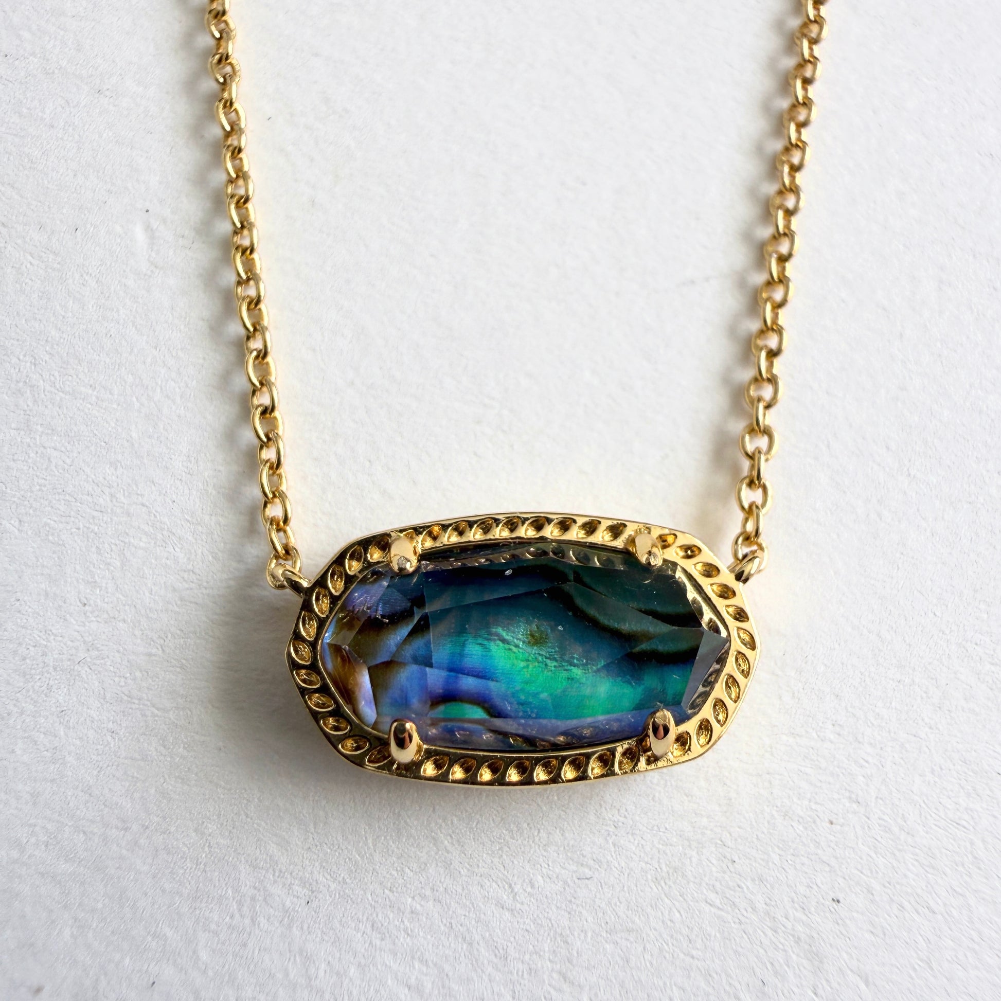 Necklace with a gold chain and colorful pendant on a white background