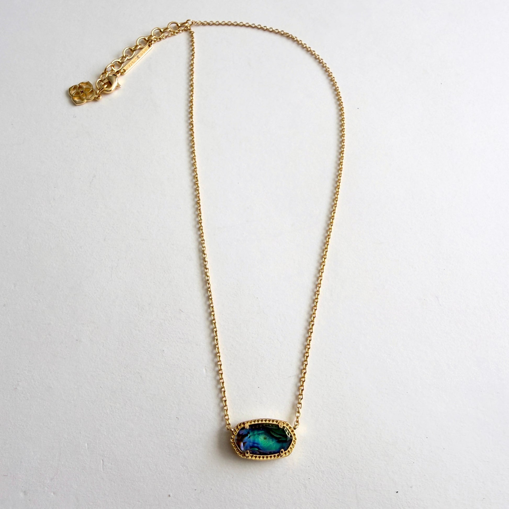 Gold necklace with a green pendant on a white background