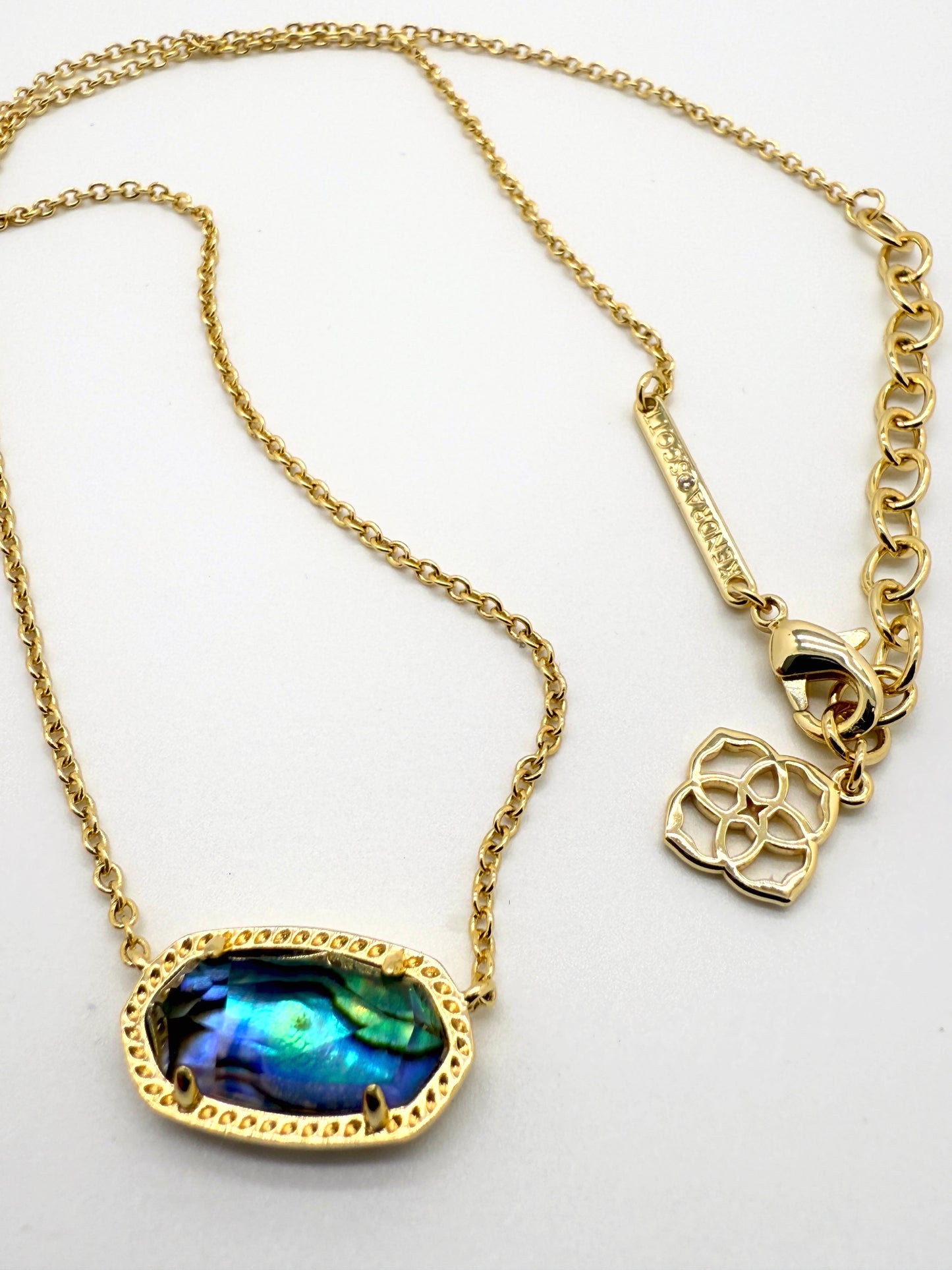 Gold necklace with a blue pendant on a white background