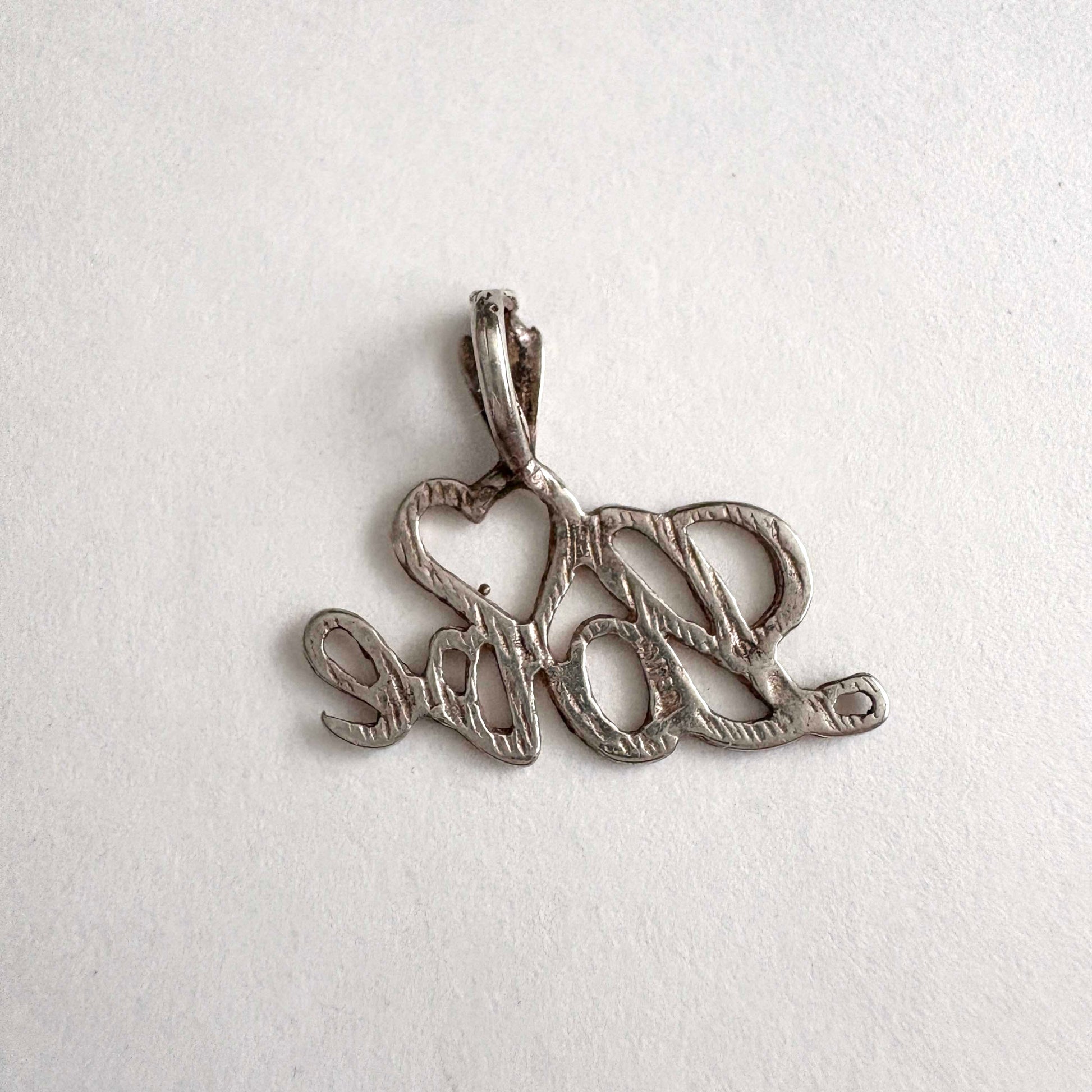 Silver pendant with 'love' on a white background