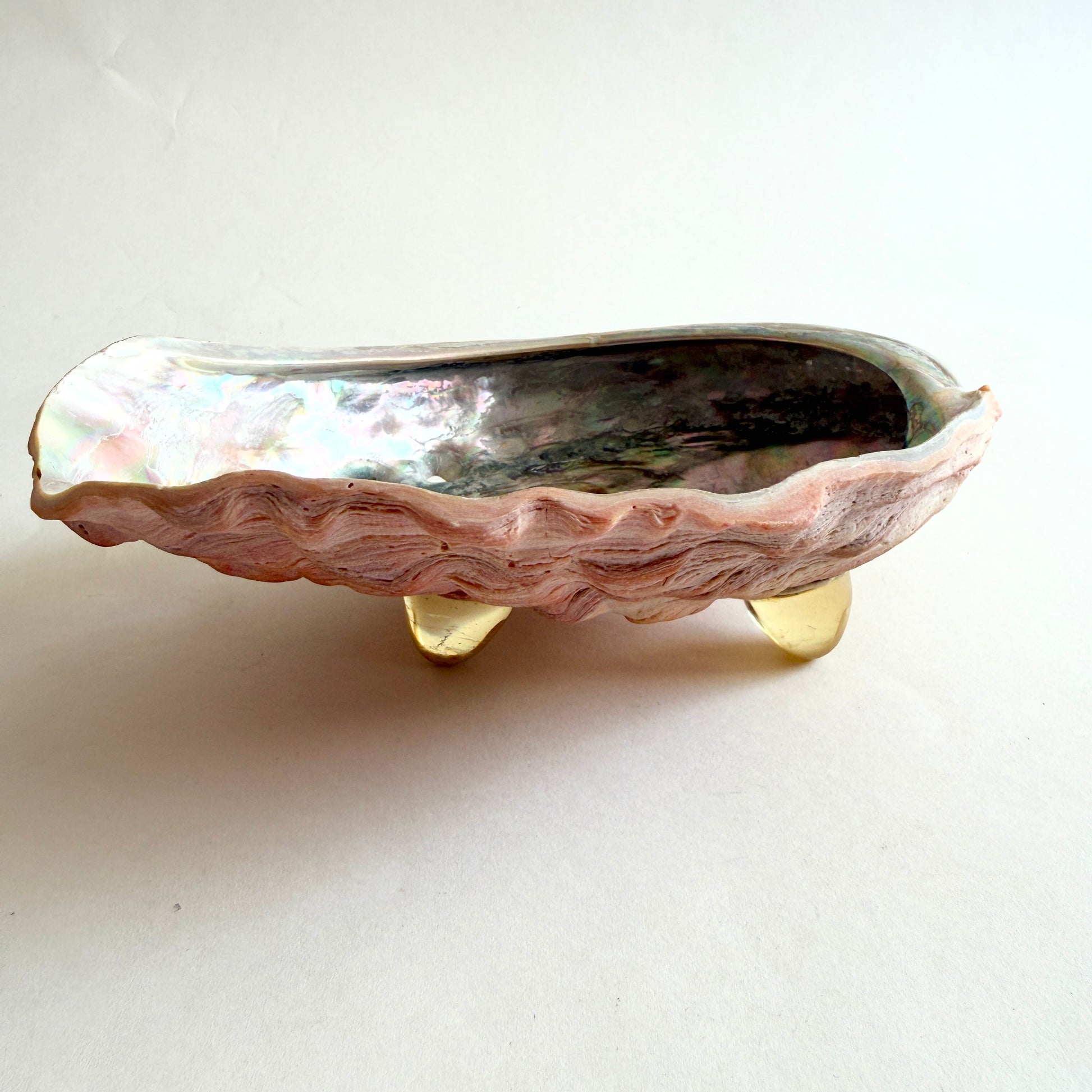 Side profile of the abalone shell bowl, showcasing the three vintage Lucite tripod feet and the floating silhouette.
