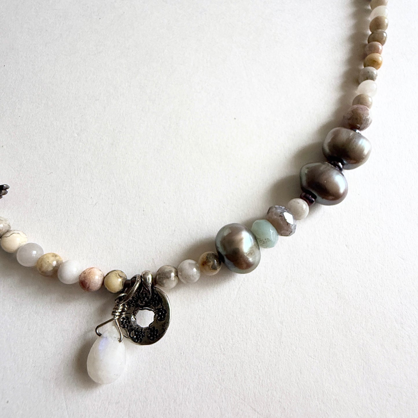 Detailed view of the organic peacock pearls and faceted agates, showcasing a palette of stormy grays and moss greens.