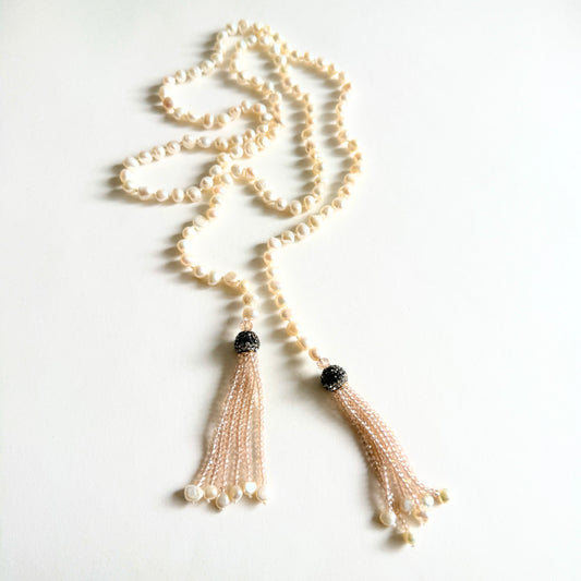 A dramatic 38-inch 'Opera length' lariat necklace featuring hand-knotted white baroque pearls and two crystalline tassels.