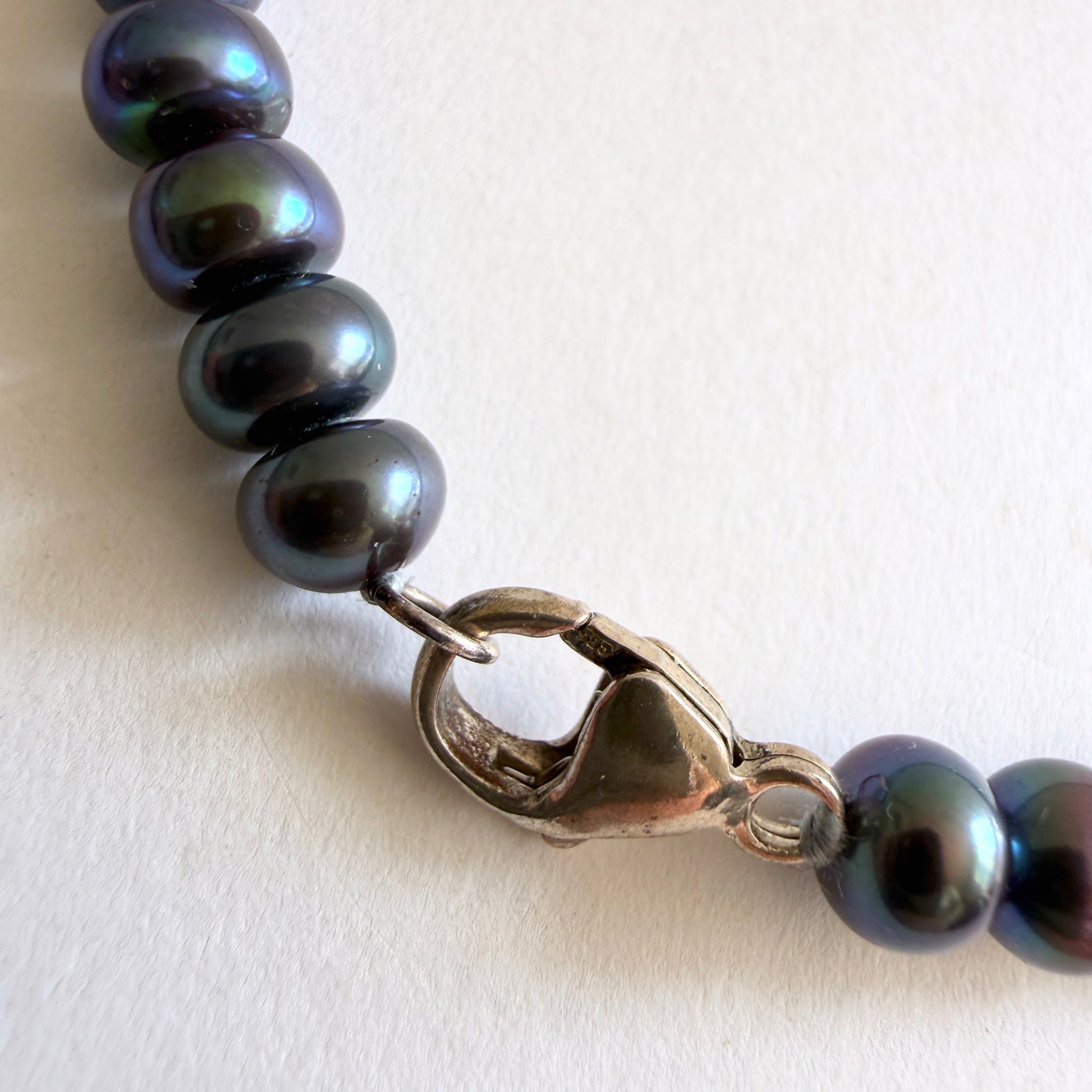 Close-up of the irregular, organic shapes of the freshwater pearls and the polished sterling silver clasp.