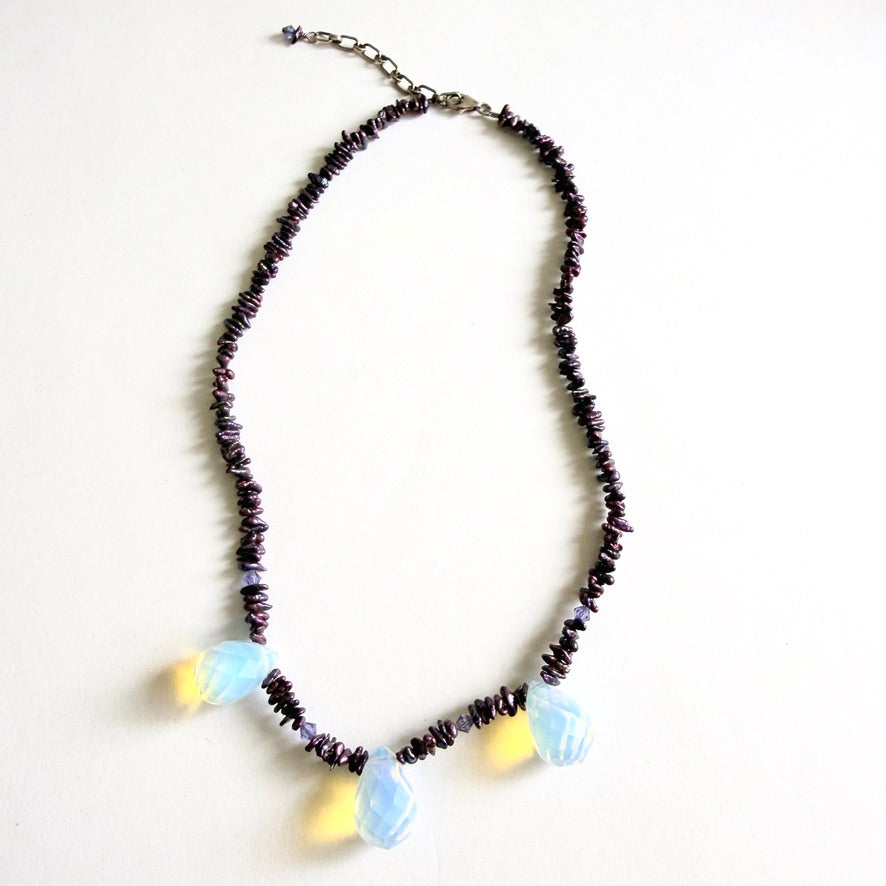 The 'Glow-Worm' necklace featuring deep merlot freshwater pearl chips and three faceted opaline glass drops on a white background.