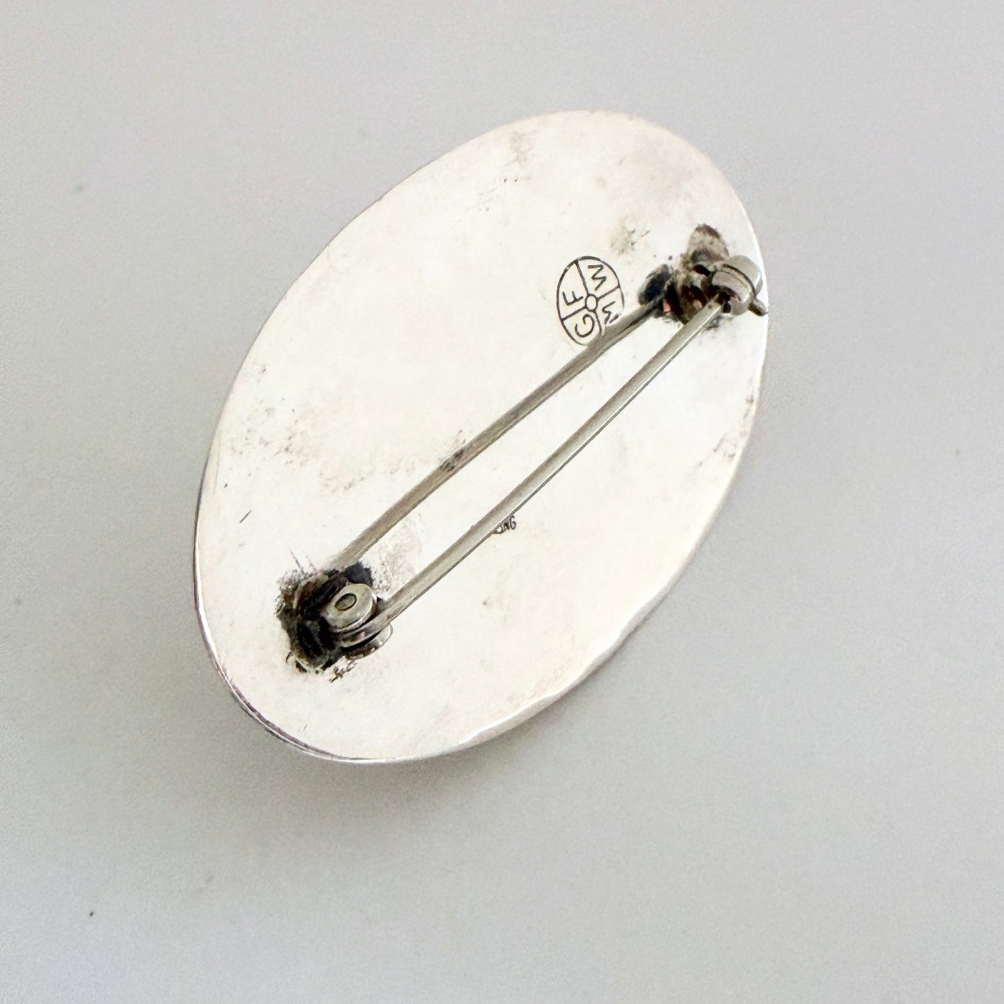 The reverse of the brooch showing the authentic 'GFMW' hallmark and the sturdy sterling silver pin mechanism.