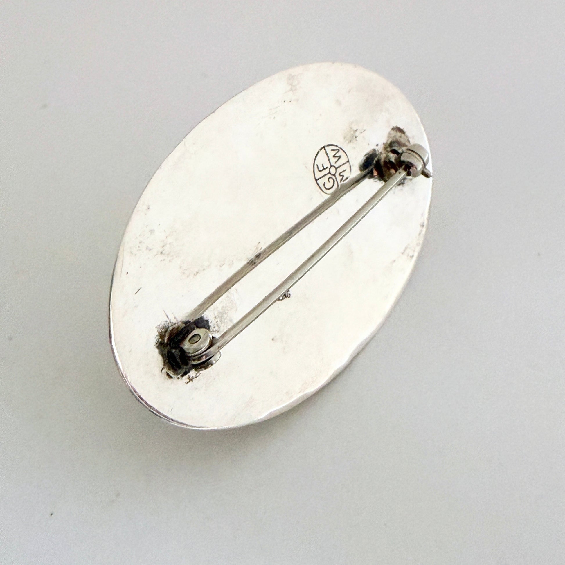 The reverse of the brooch showing the authentic 'GFMW' hallmark and the sturdy sterling silver pin mechanism.