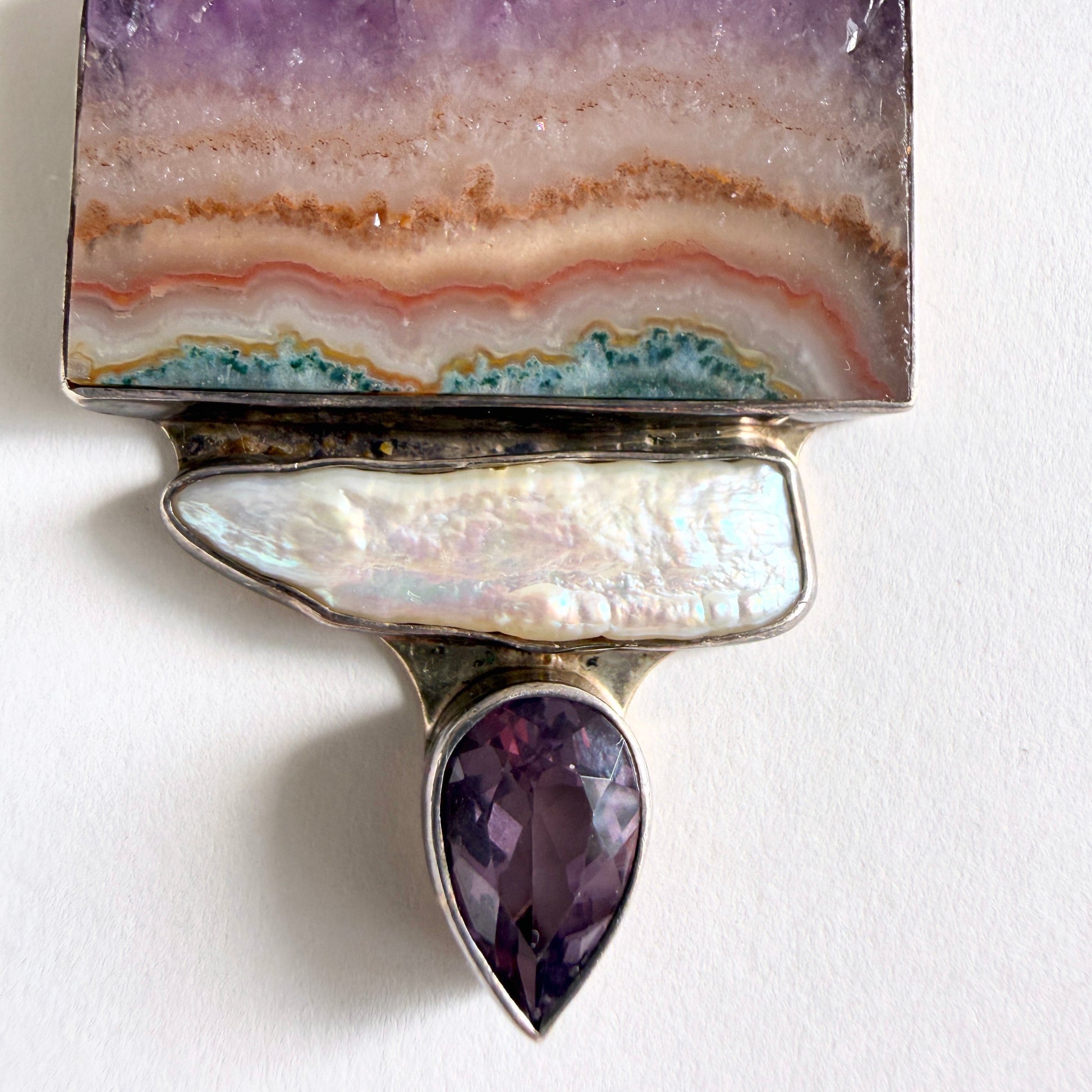 Close-up of the amethyst stalactite slice, showing concentric geological banding in neutral and earth tones.