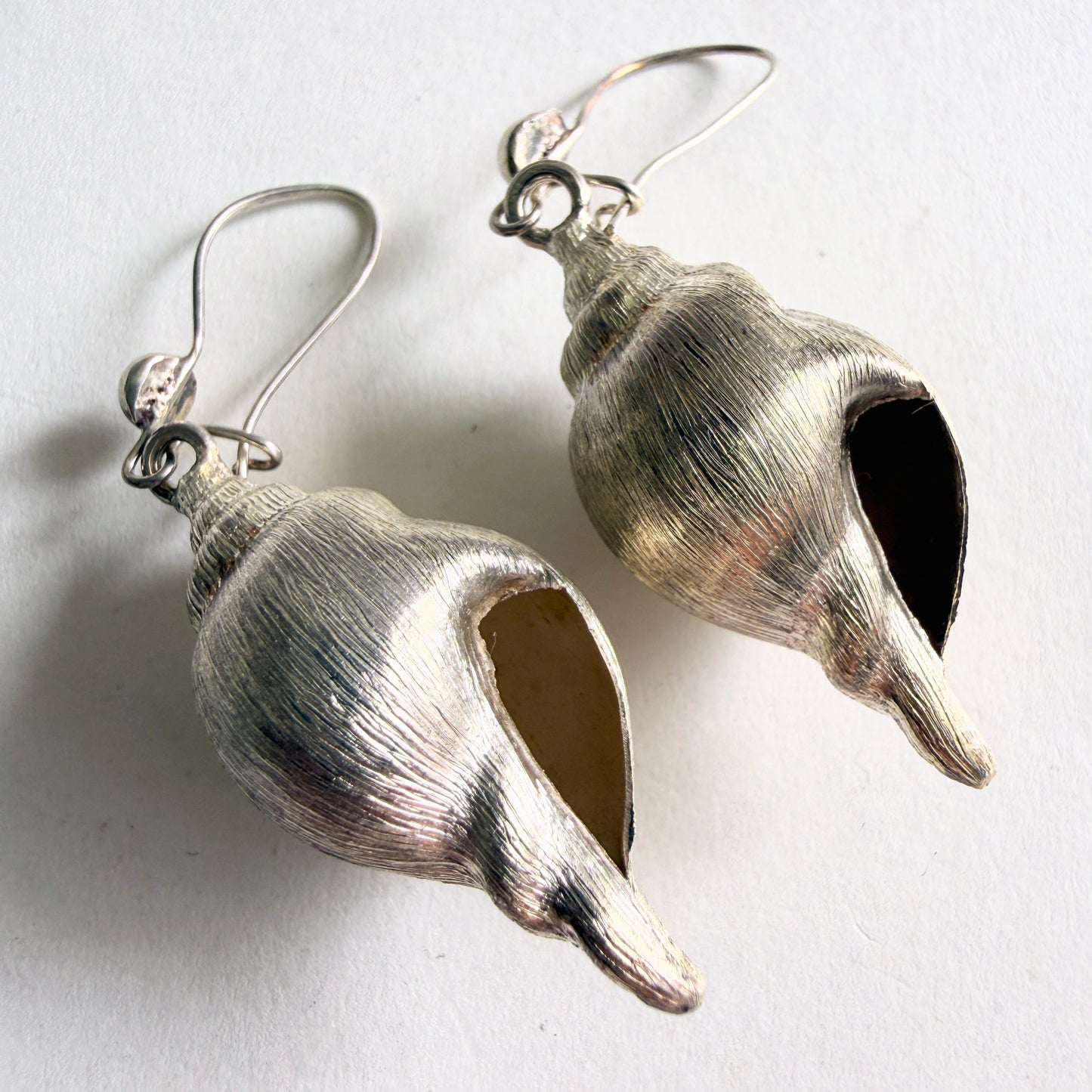 Detailed view of the ribbed texture and maritime realism of the sterling silver conch shell drops.