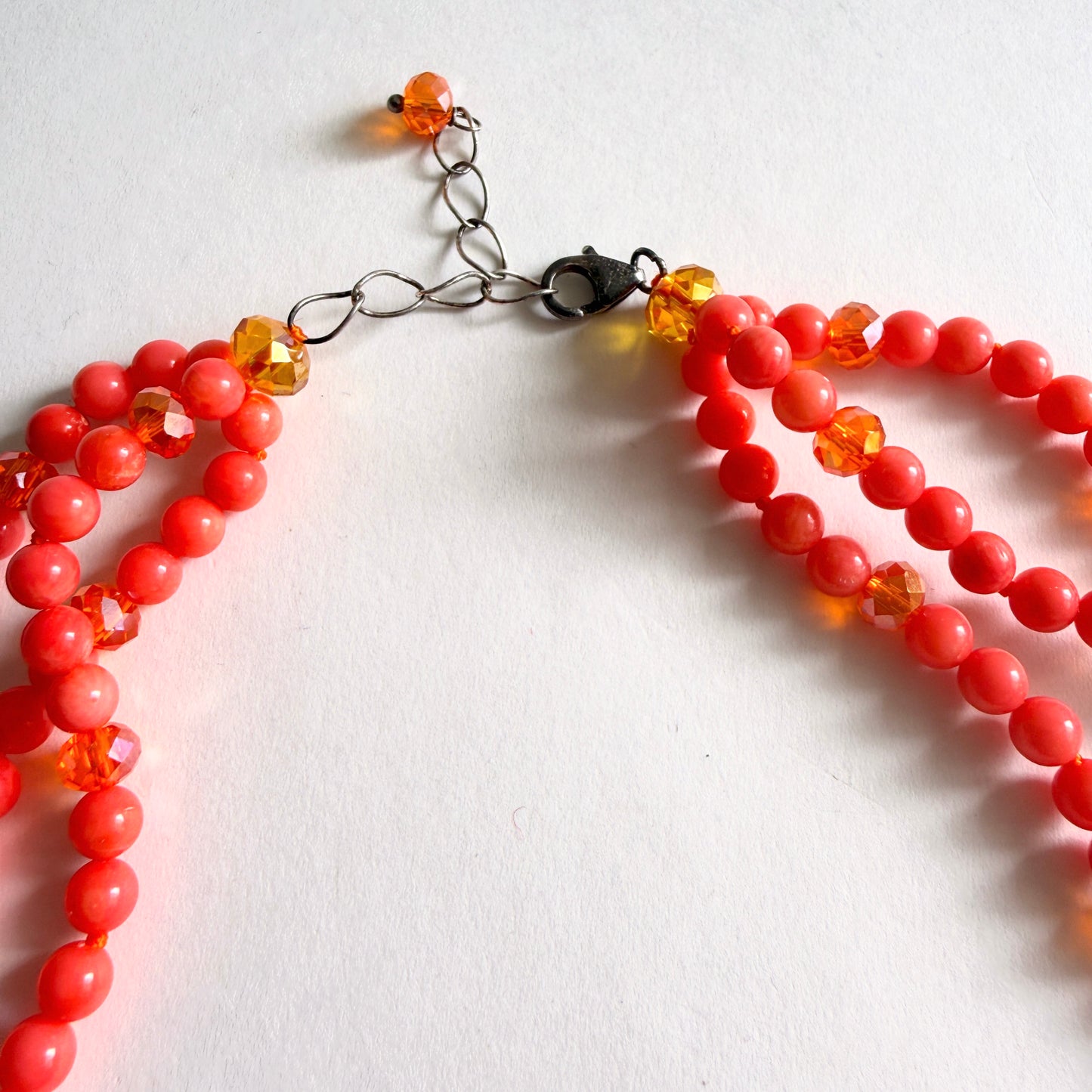 Detailed view of the adjustable sterling silver extender chain and lobster claw clasp on a coral beaded necklace.