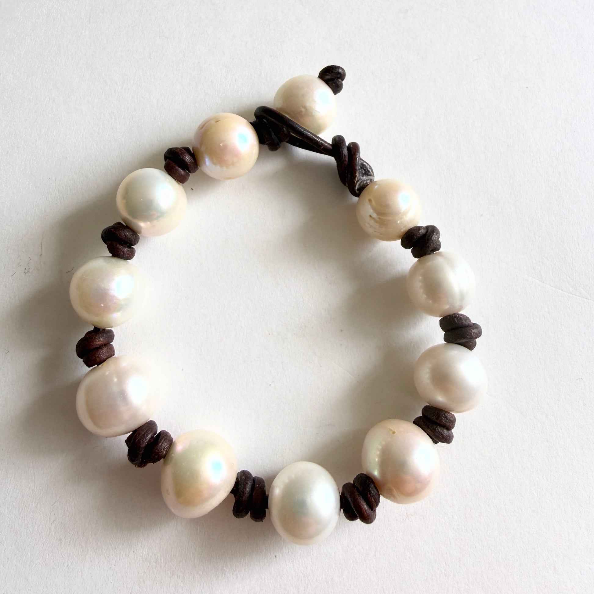 Full view of the 'Tide-Line' bracelet featuring large high-luster baroque pearls hand-knotted on dark brown leather cord.