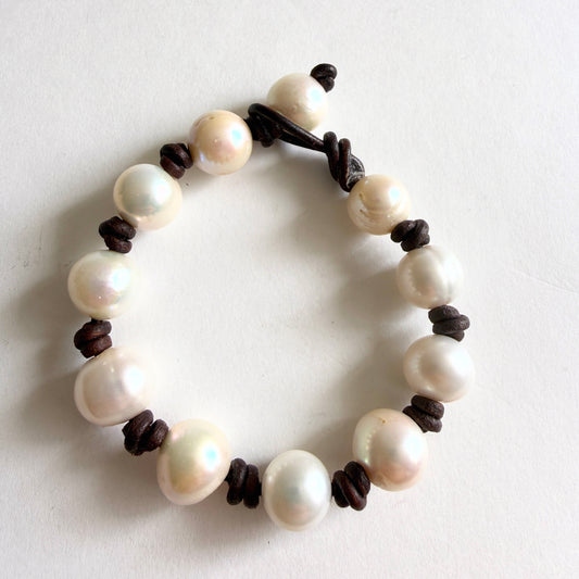 Full view of the 'Tide-Line' bracelet featuring large high-luster baroque pearls hand-knotted on dark brown leather cord.