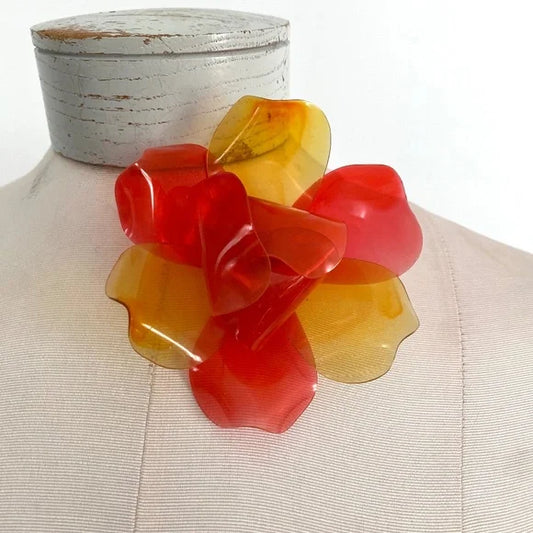 Vintage 1960s translucent red and yellow layered flower brooch made from cellulose acetate presented on a mannequin on a white background
