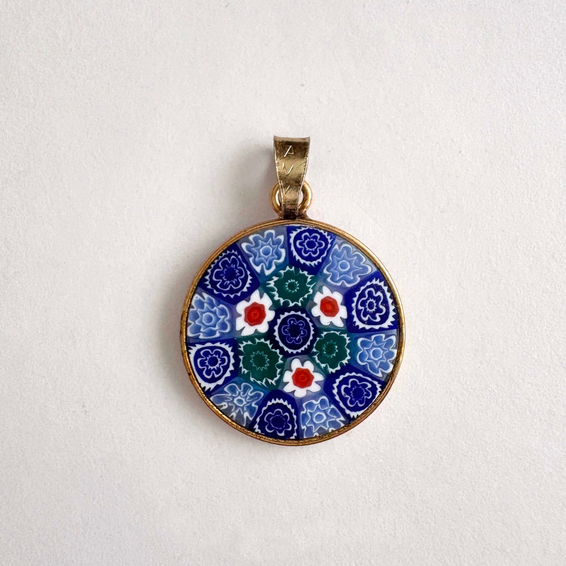 round floral Millefiori glass pendant with gold frame on a white background