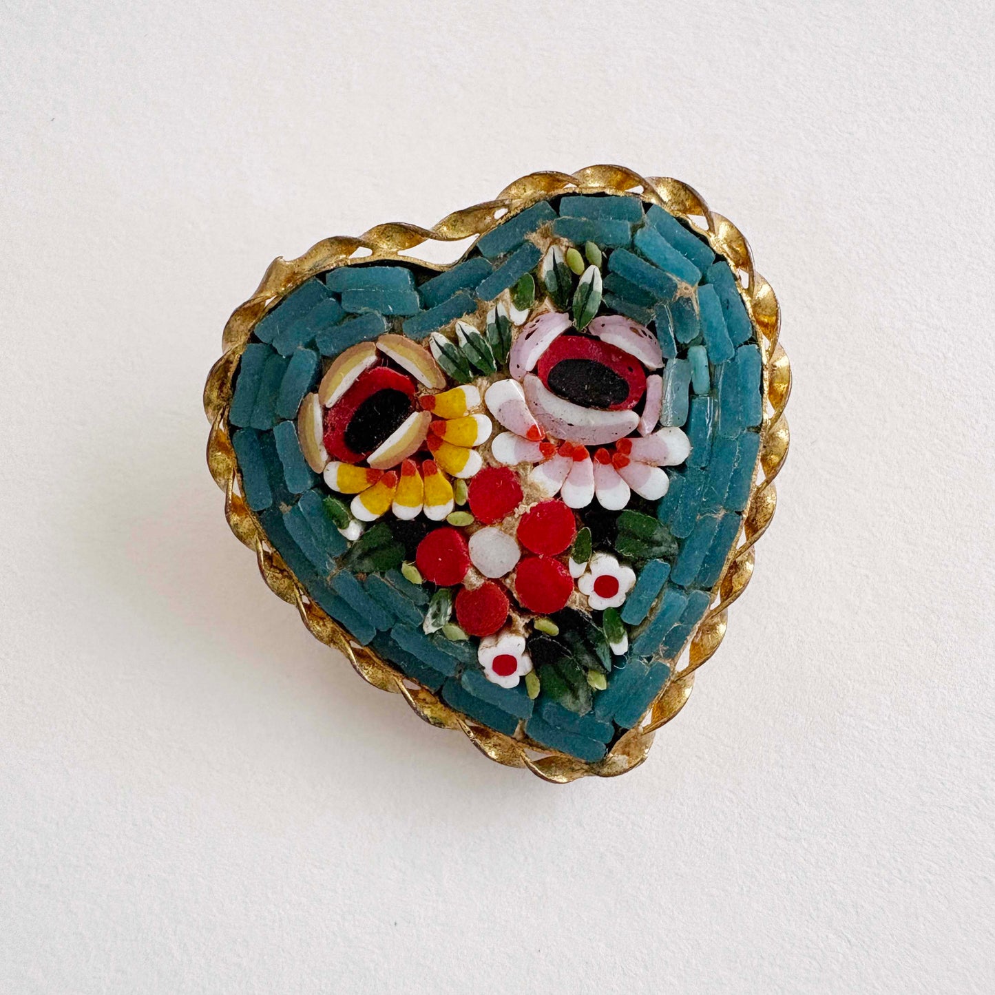 Heart-shaped brooch with mosaic floral design on a white background